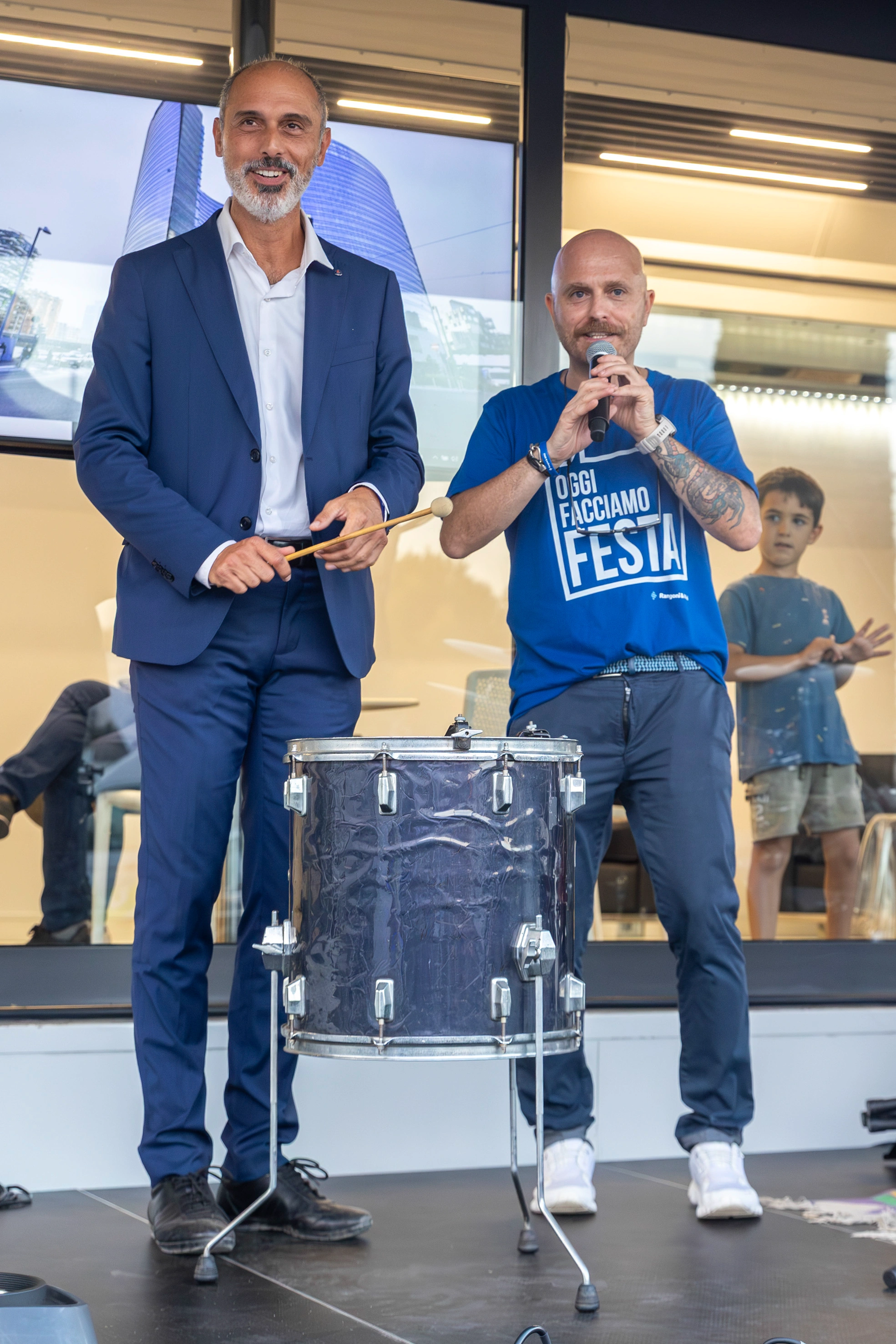 Due uomini in piedi su un palco con una batteria.