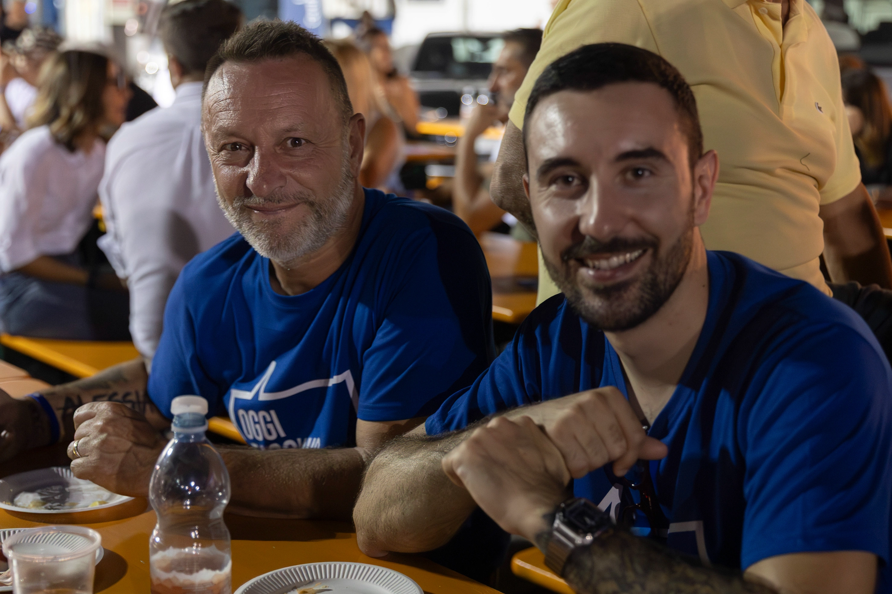 Due uomini sorridenti seduti a un tavolo.