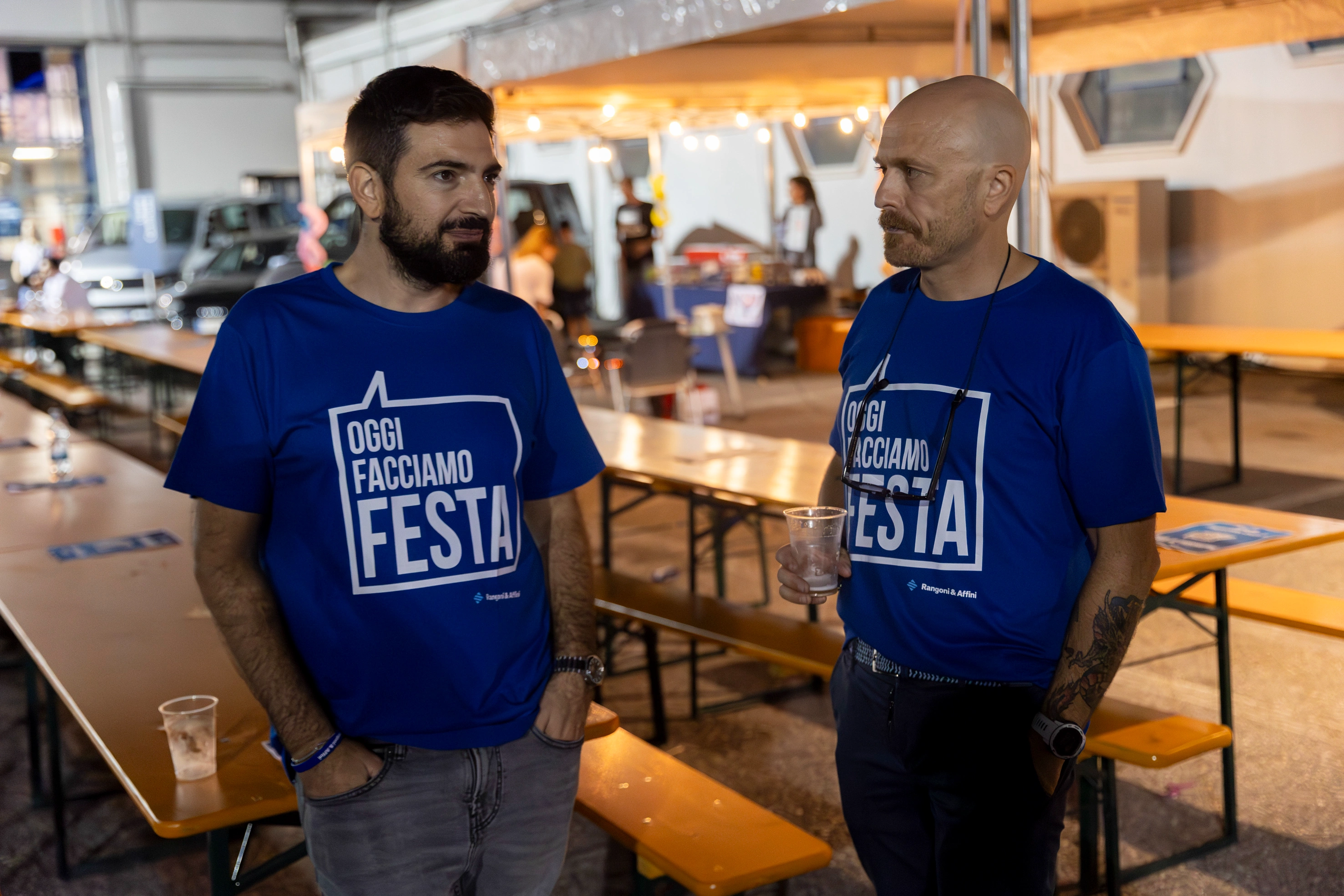 Due uomini indossano magliette blu con scritto "Oggi Facciamo Festa".