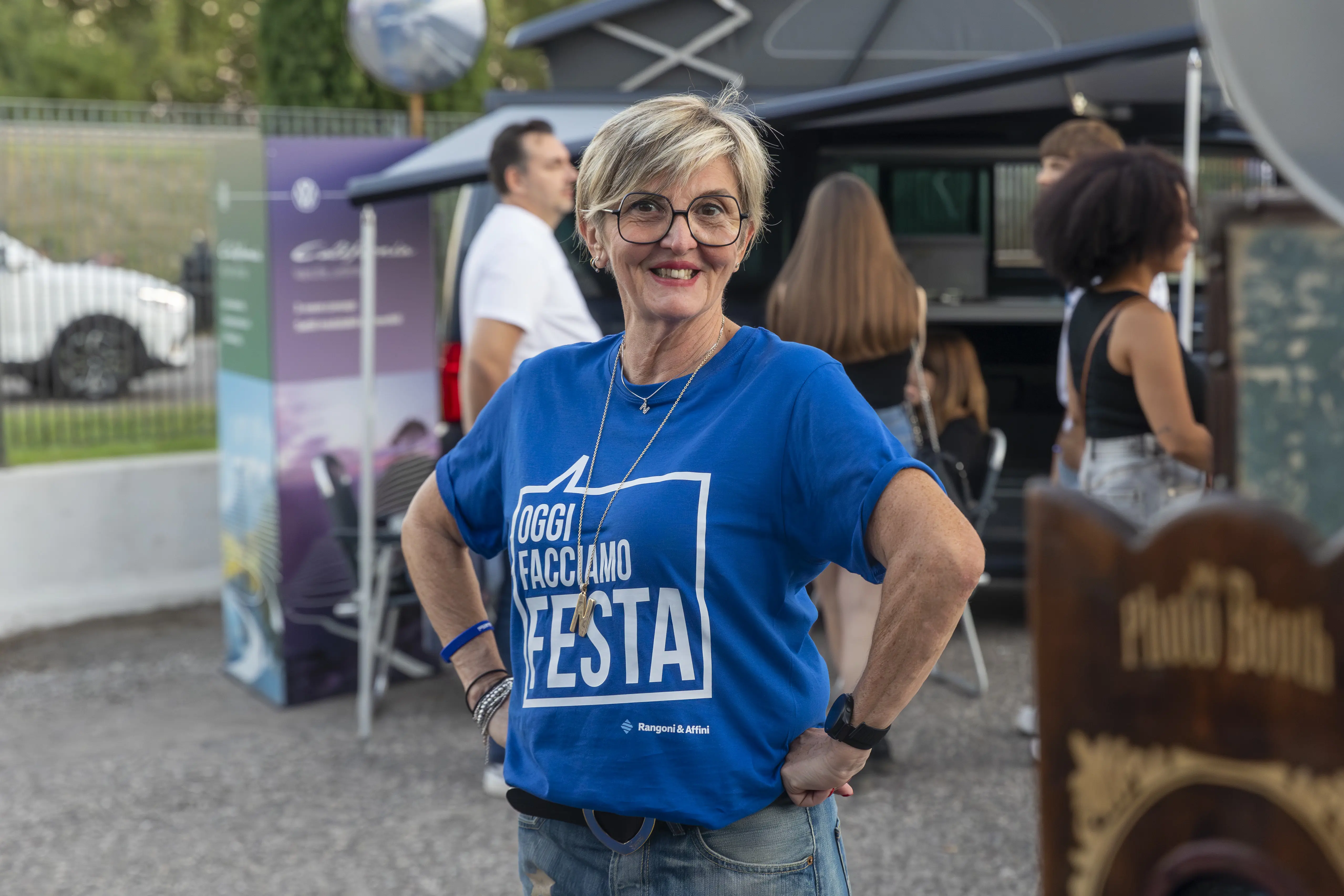 Donna sorridente in una maglietta blu con la scritta "Oggi facciamo festa".