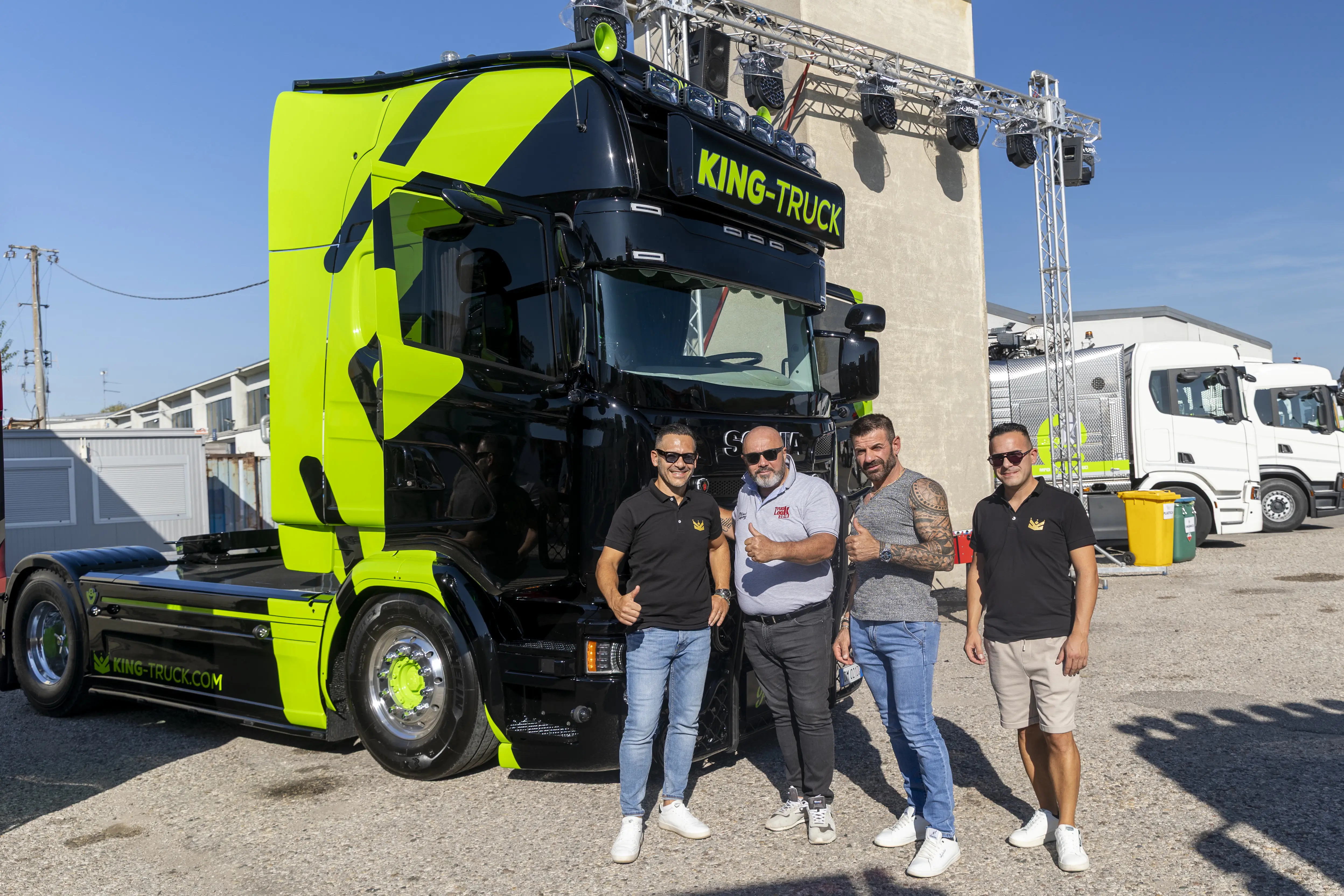 Quattro uomini posano accanto a un camion giallo e nero con la scritta "KING-TRUCK".