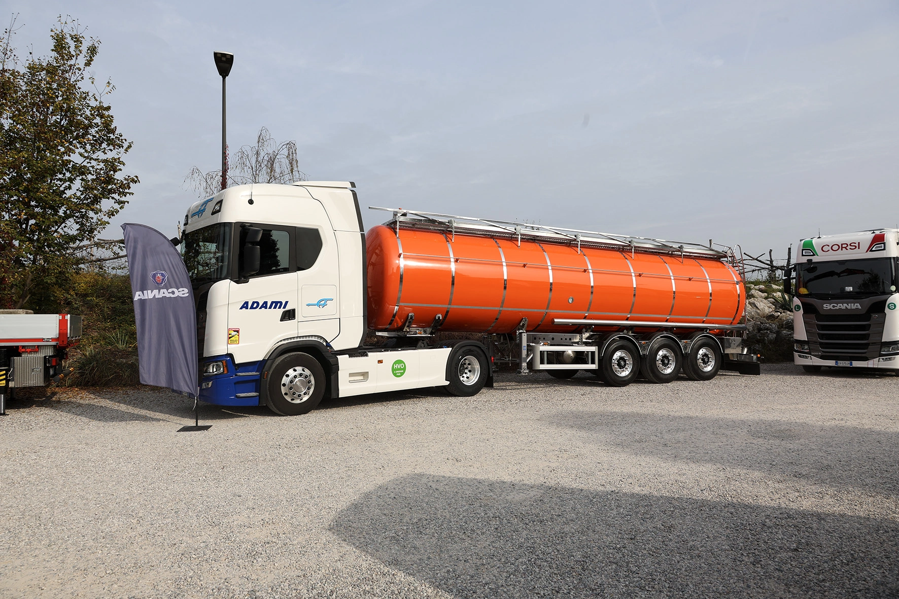 Un camion cisterna arancione con un rimorchio parcheggiato in un lotto.