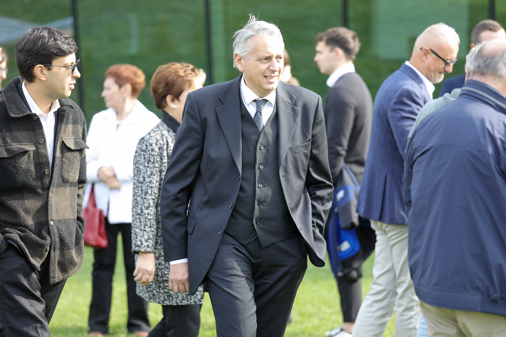 Uomini in abiti formali e casual su un prato.