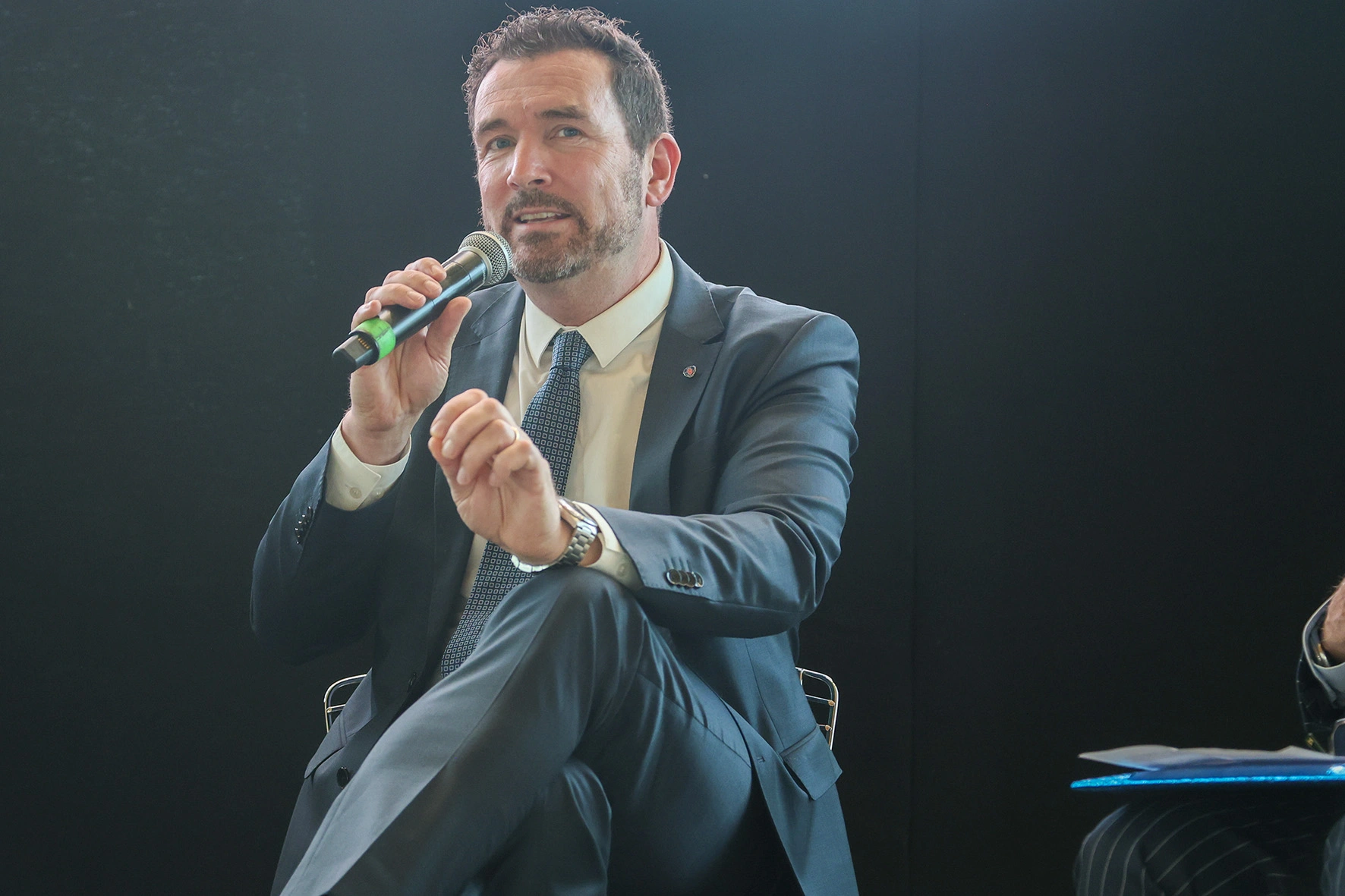 Uomo in giacca e cravatta che parla al microfono.