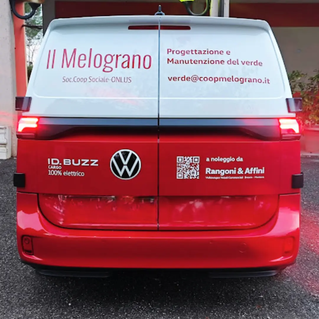 Il retro di un furgone rosso e bianco Volkswagen ID.Buzz con la scritta "Il Melograno" e "100% elettrico".