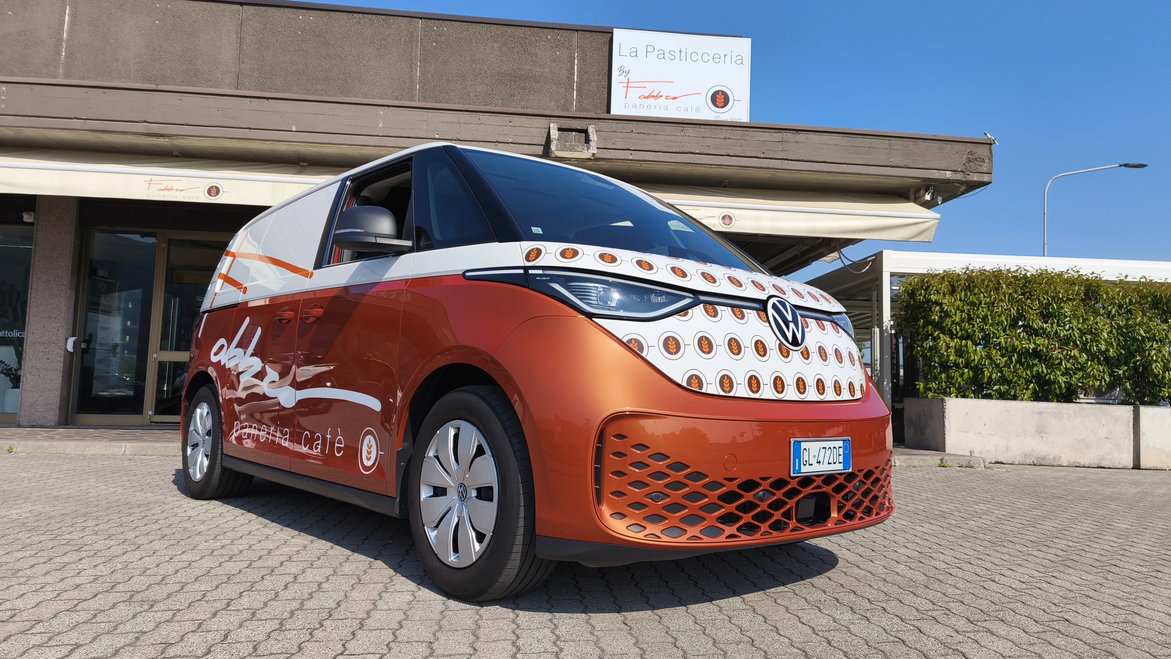 Un furgone VW ID.Buzz di "Fabbro paneria café" parcheggiato davanti alla pasticceria.
