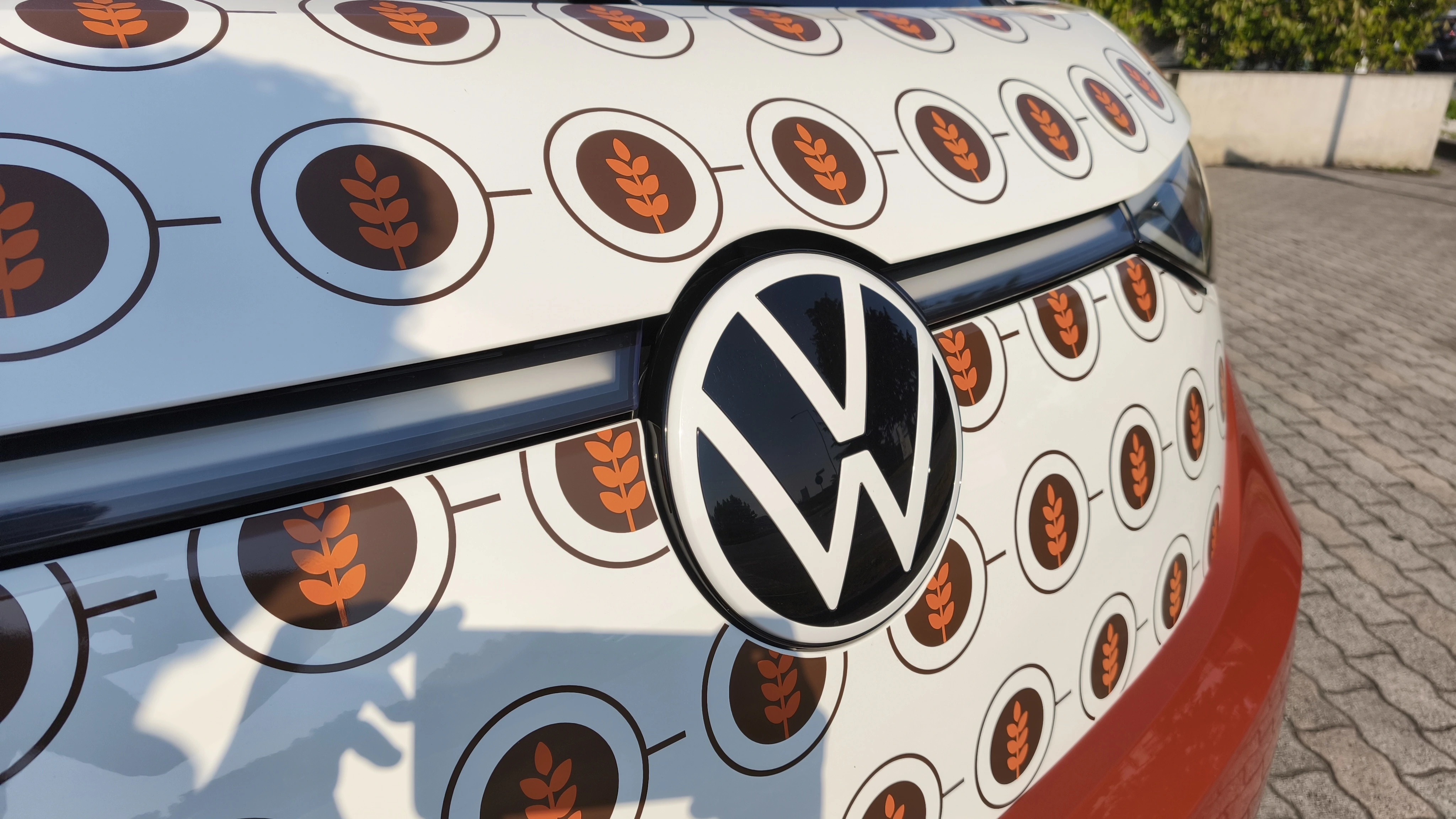 Un primo piano del logo Volkswagen su un'auto ricoperta di immagini di grano.