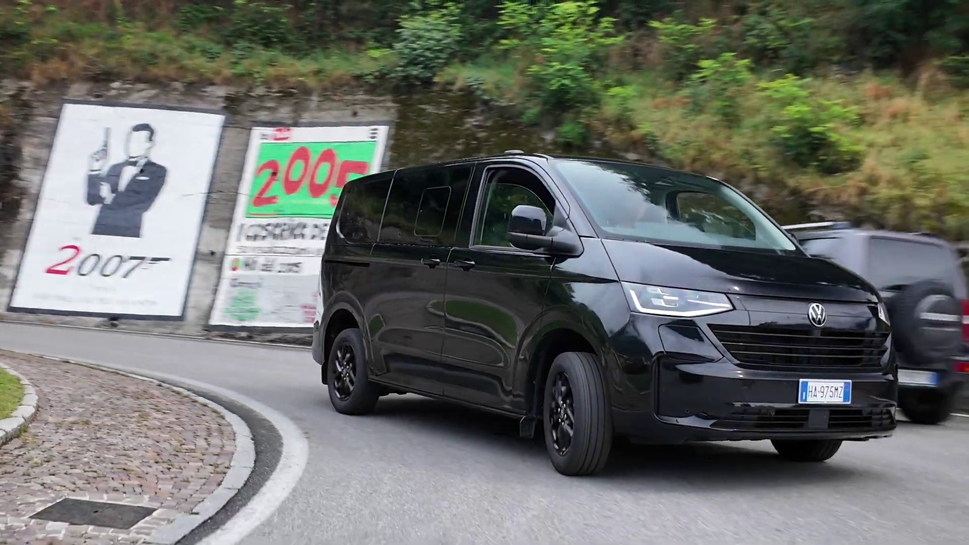 Un furgone Volkswagen nero viaggia su una strada tortuosa di montagna.