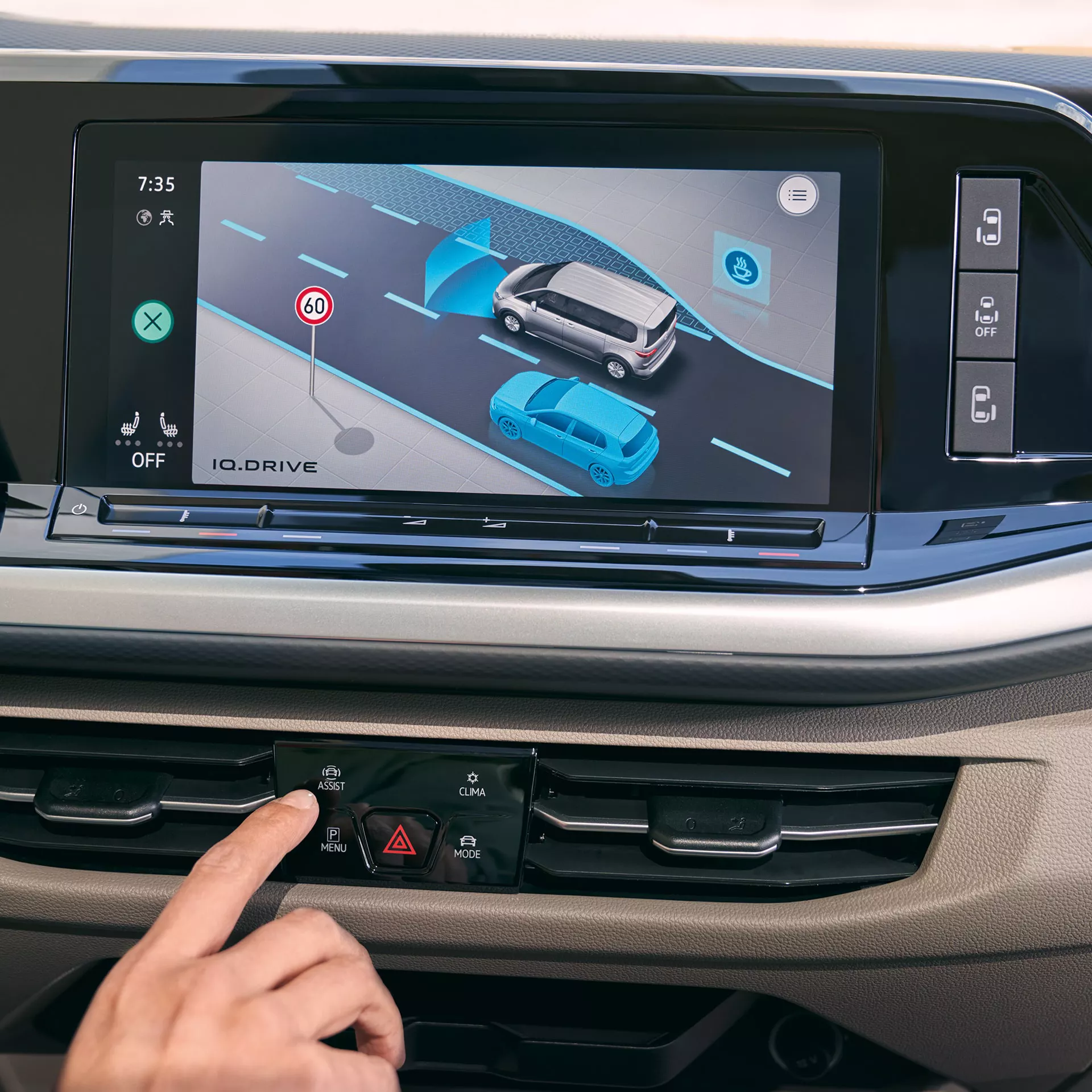 Il dito preme il pulsante Assist sulla plancia di una Volkswagen. Sullo schermo appare la funzione IQ.DRIVE.