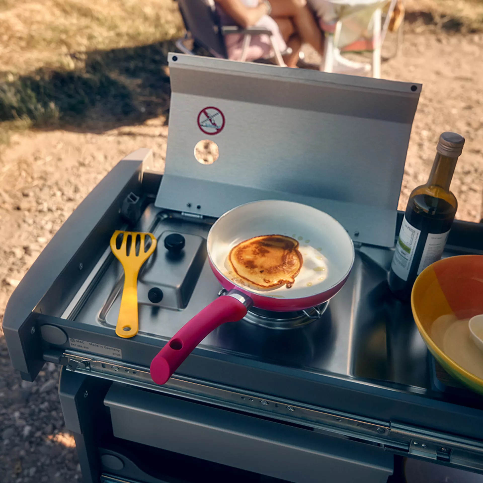 Una frittella in cottura su un fornello portatile all'aperto.