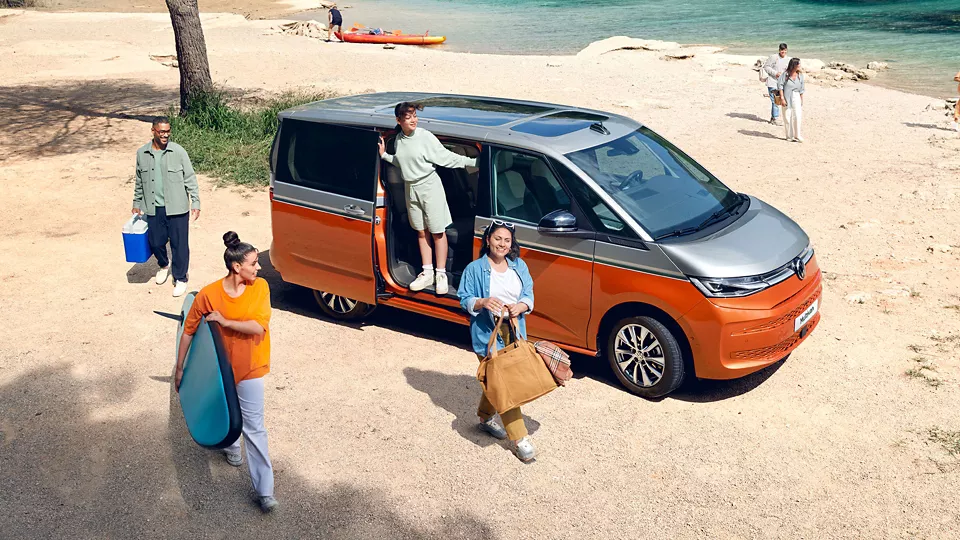 Una famiglia che fa un'escursione alla spiaggia in un furgone Volkswagen Multivan.