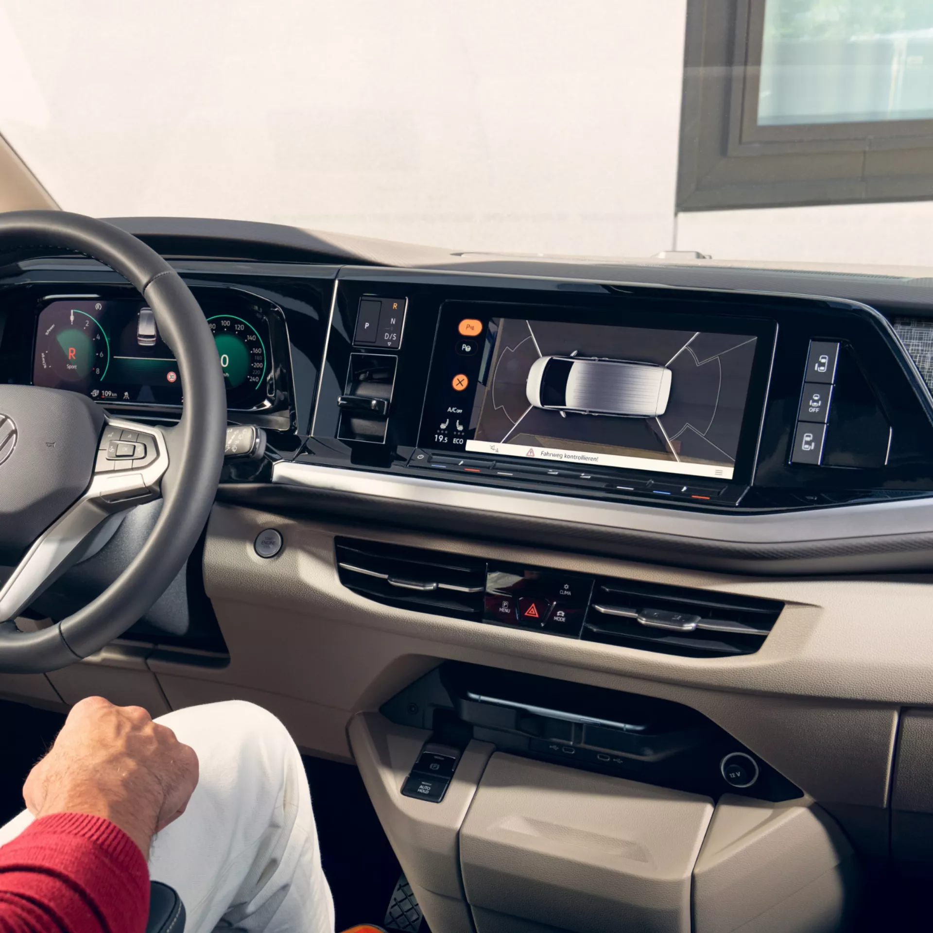 Interni di un'auto moderna con display digitale che mostra una vista dall'alto. La macchina è in retromarcia.