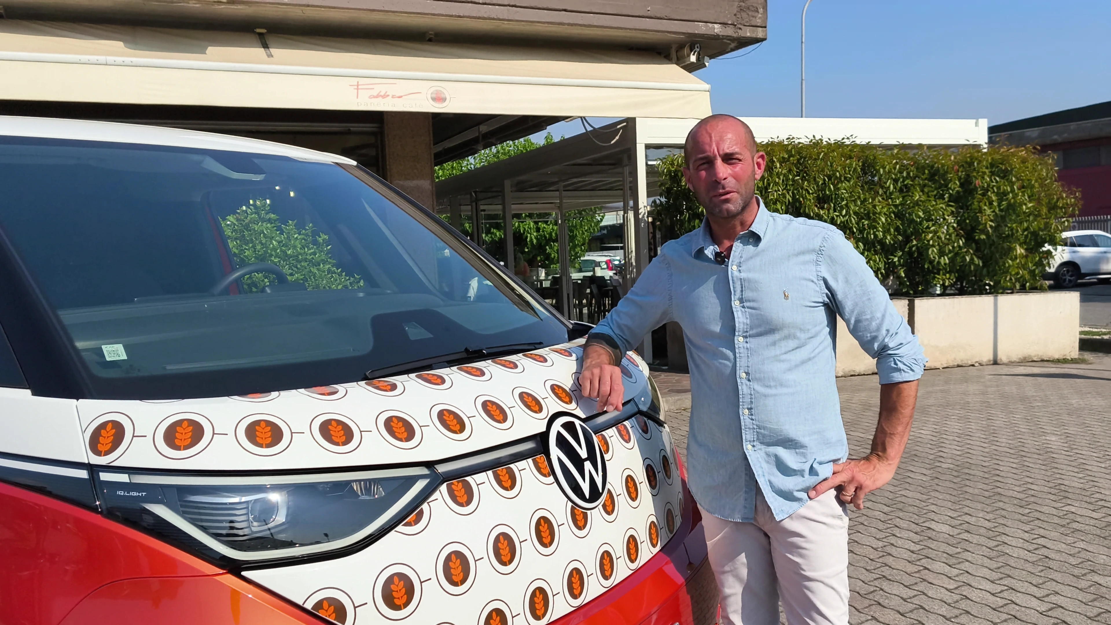 Uomo in posa accanto a un furgone Volkswagen personalizzato.