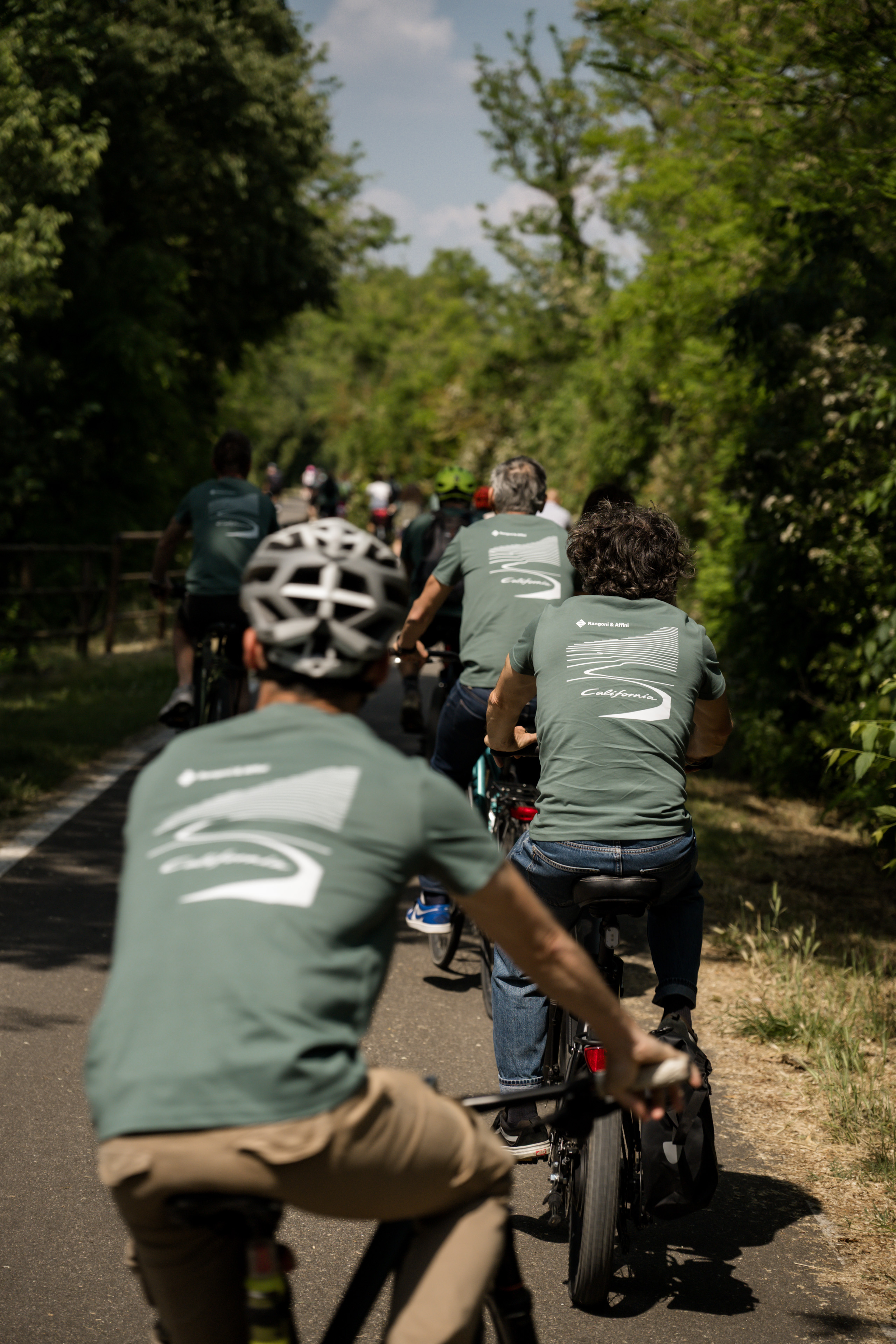 Gita in bici di gruppo su un sentiero ombreggiato tra gli alberi.