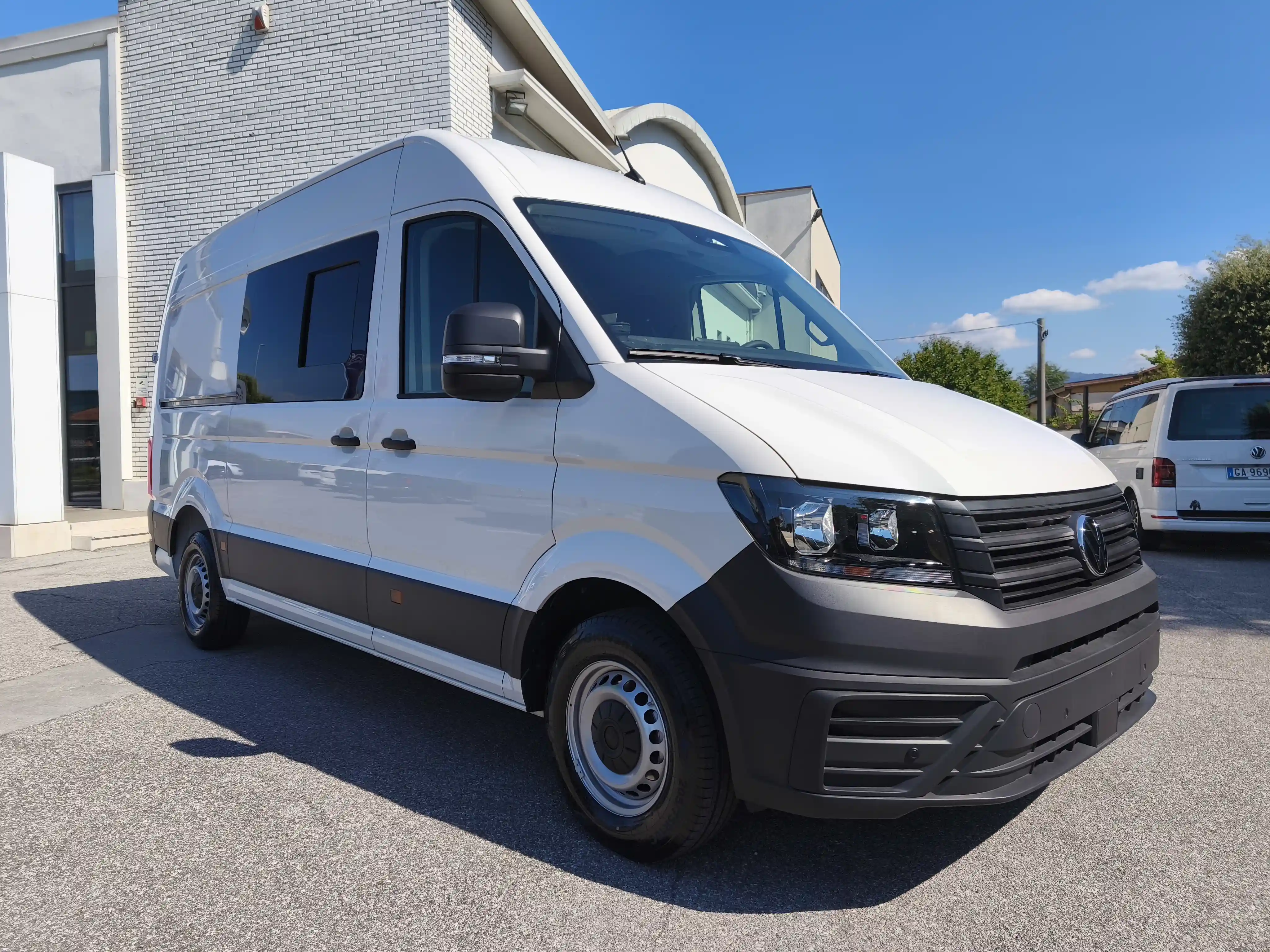 Un furgone bianco Volkswagen parcheggiato di fronte a un edificio.