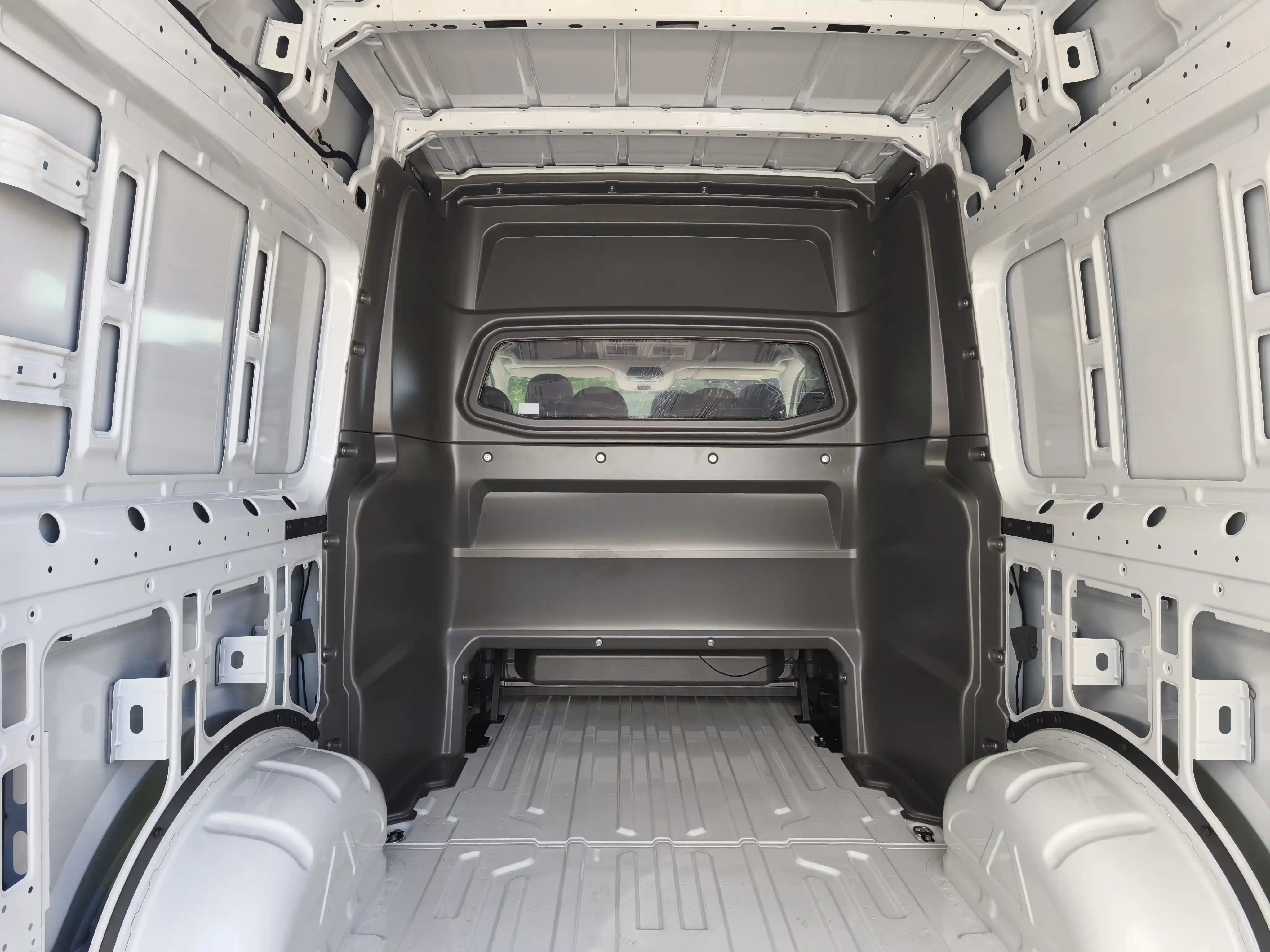 Interno di un furgone bianco con una barriera tra l'abitacolo e il vano di carico.