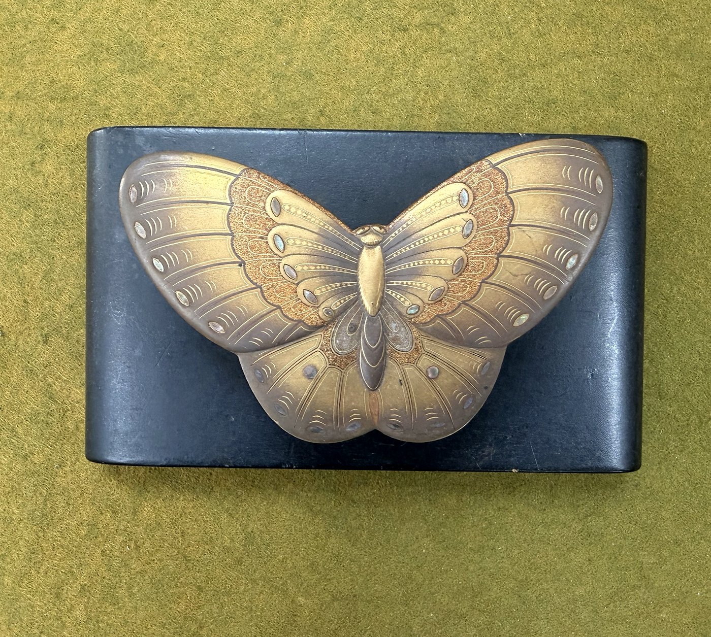 A gold lacquer box in the shape of a butterfly, seen from above on a black stand