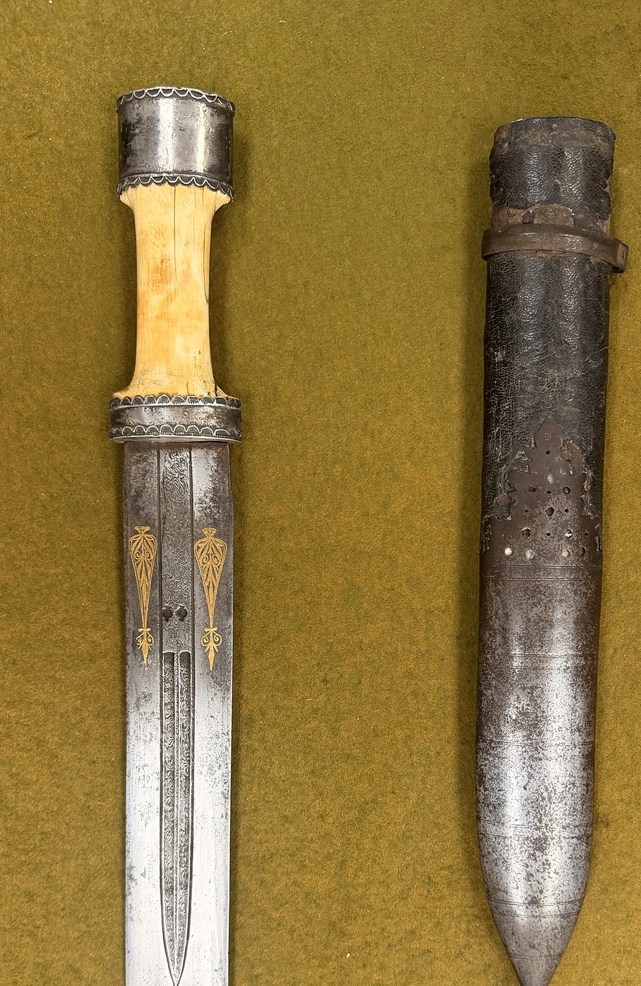 A double-edged blade with a pale grip and gold-inlaid palmettes, beside its scabbard