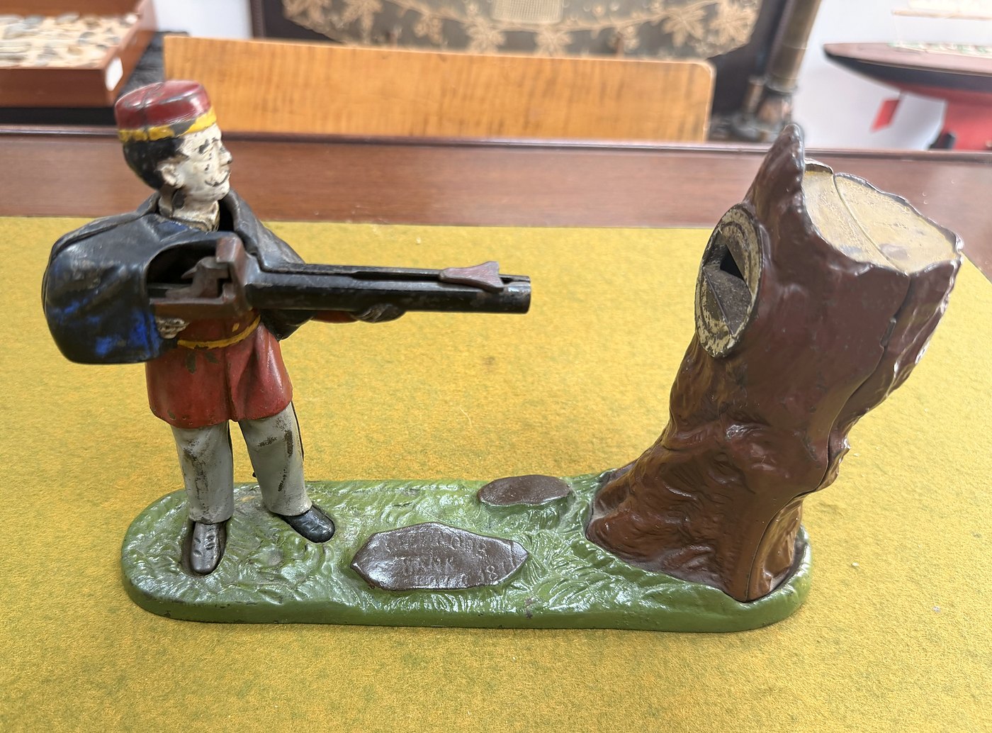 A painted cast-iron mechanical bank: a soldier aiming at a tree stump
