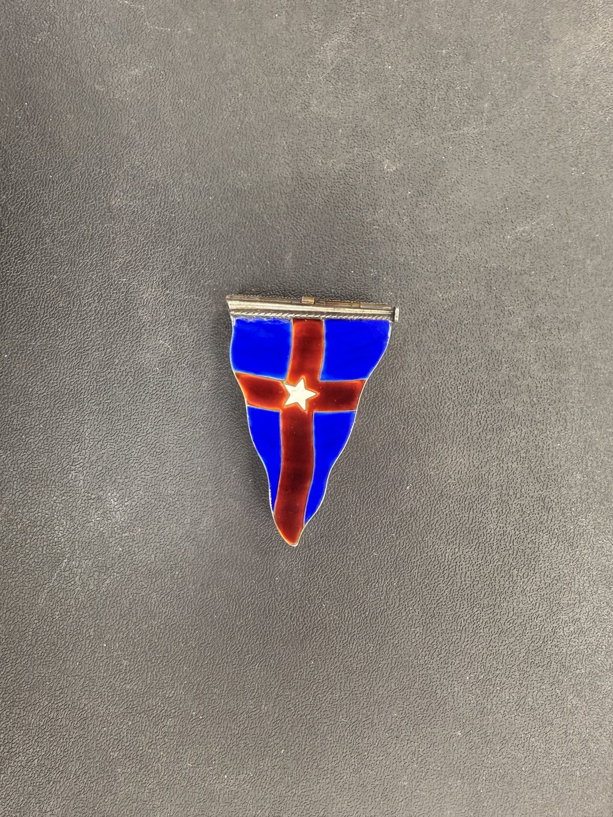 An enamel pennant, blue with a red cross and a white star, on a metal bar