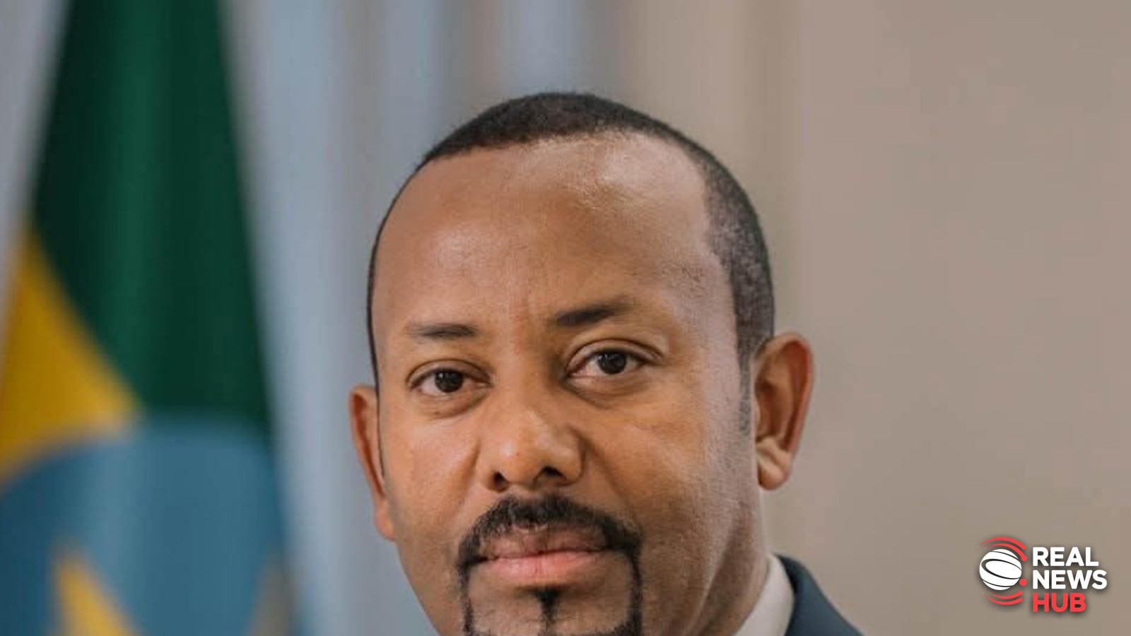 Official portrait of Ethiopian Prime Minister Abiy Ahmed wearing a dark suit and tie in front of the Ethiopian flag.