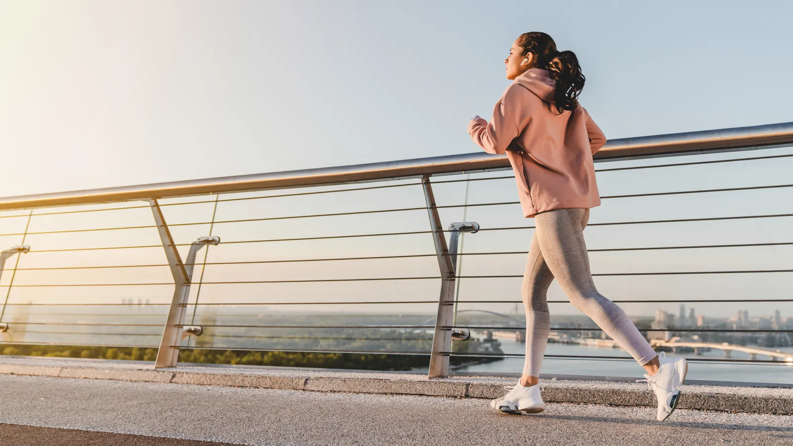 Woman walking briskly along a seaside promenade at first light