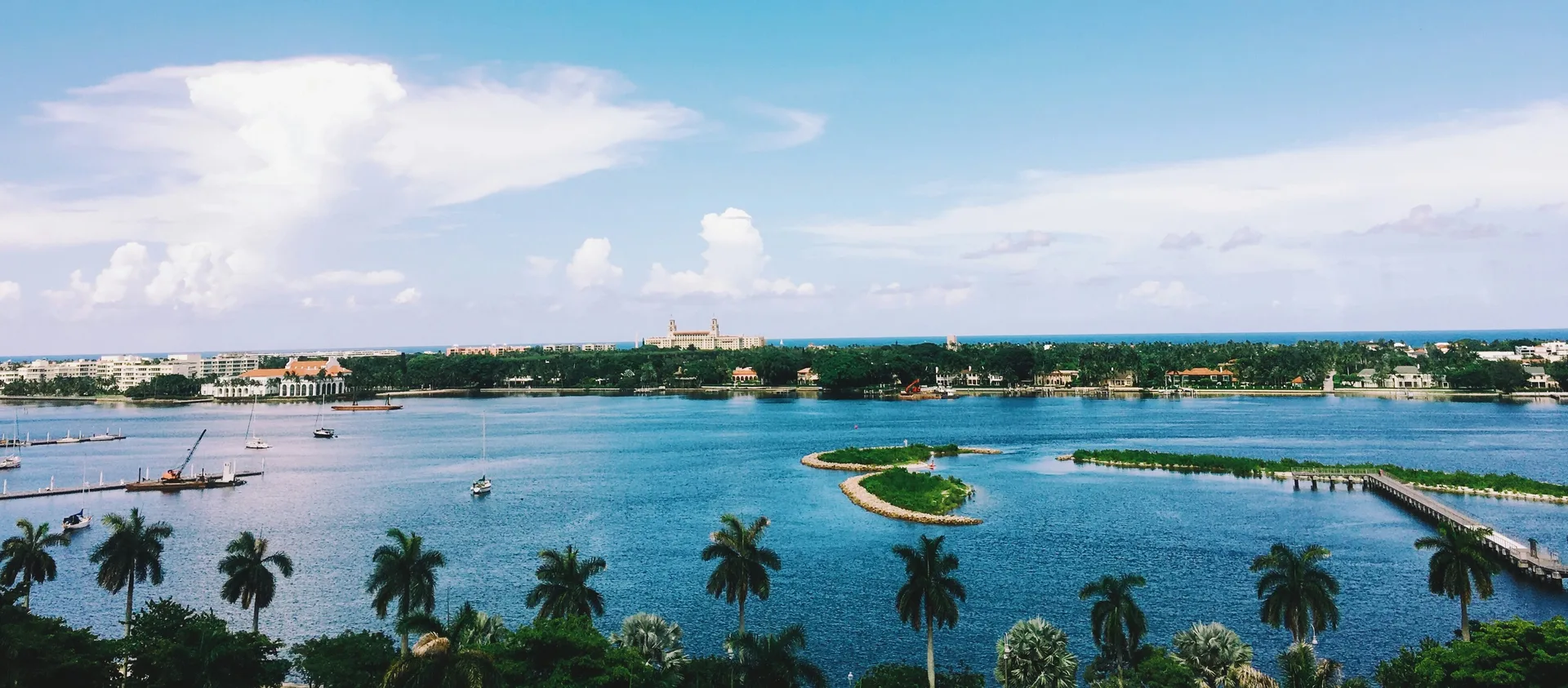 View across the Lake Worth Lagoon toward Palm Beach Island, with palm trees in the foreground
