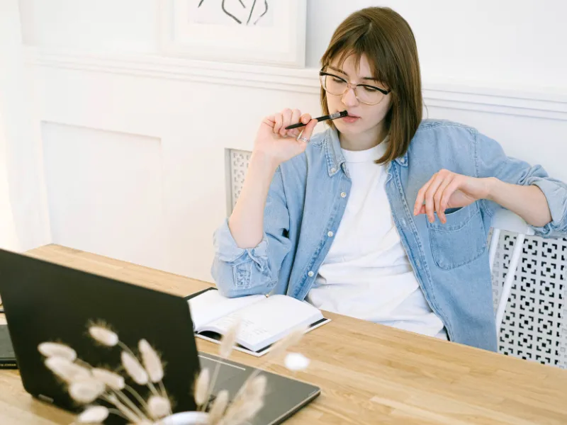 Mujer pensando frente a su computadora, probablemente se pregunte si Se puede vivir de un blog