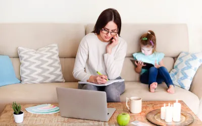 Imágen ilustrativa, una mamá trabajando desde su casa mientras atiende a su hija