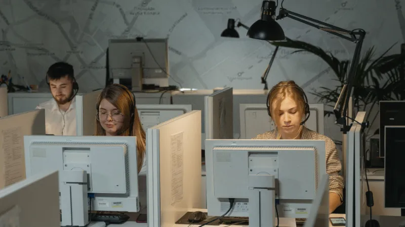 Personas trabajando en atención al cliente con auriculares frente a sus computadoras