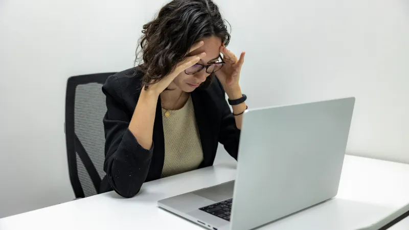 Mujer agotada frente a su notebook después de horas buscando trabajo