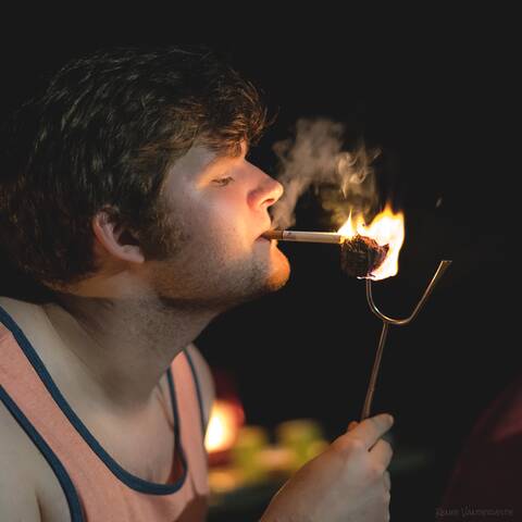 Photo of a person lighting a cigarette with a mashmallow.