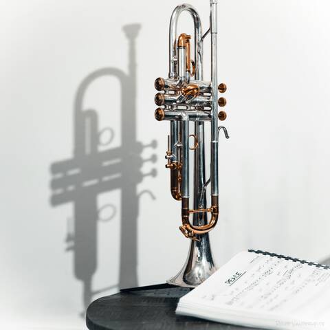 A trumpet stood on a table, with a music book open to the song titled 'peace'