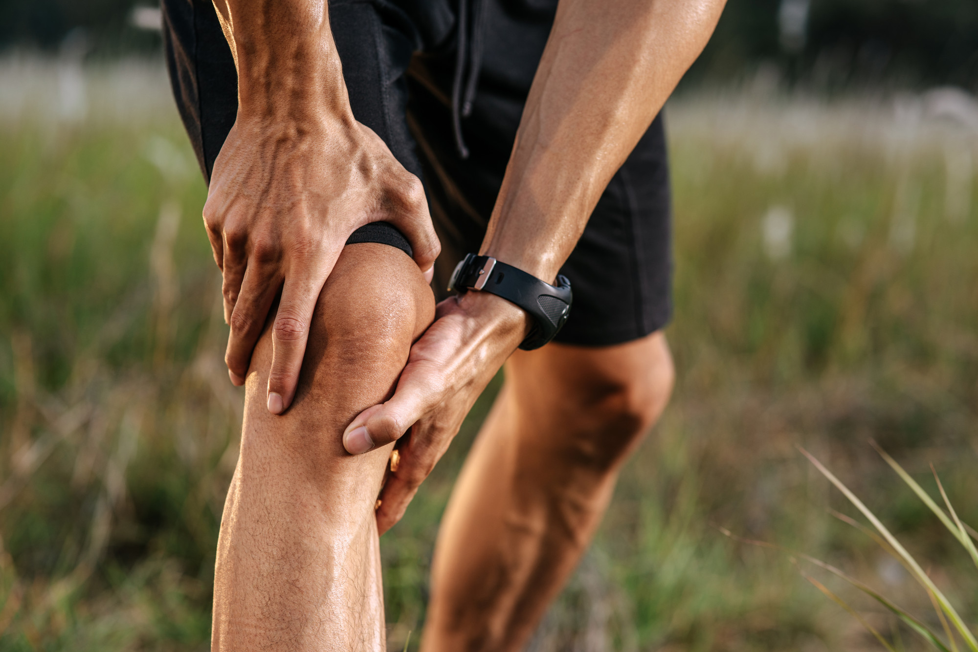 A man holding his knee after a run.