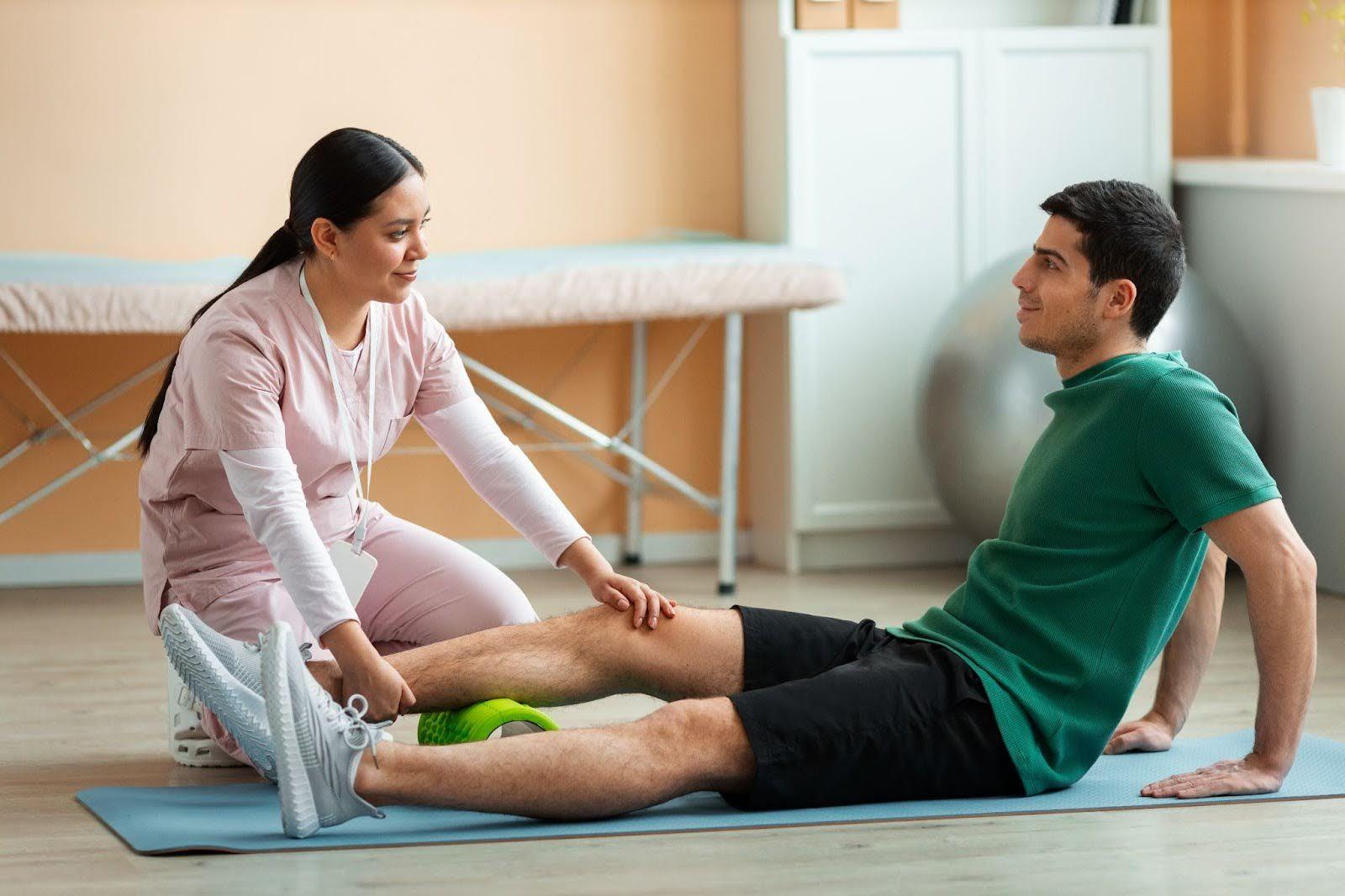 Doctor helping a patient with floor stretches with rolling foam.