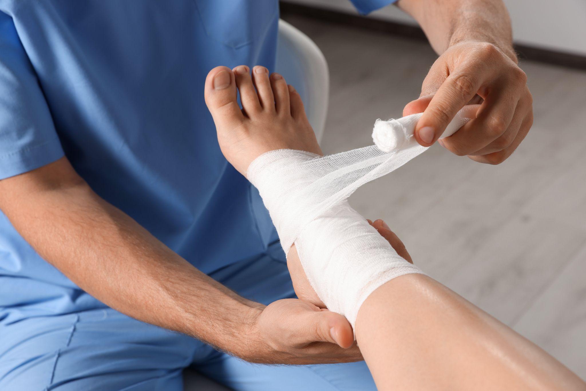 A doctor wrapping a bandage on a patient's leg.