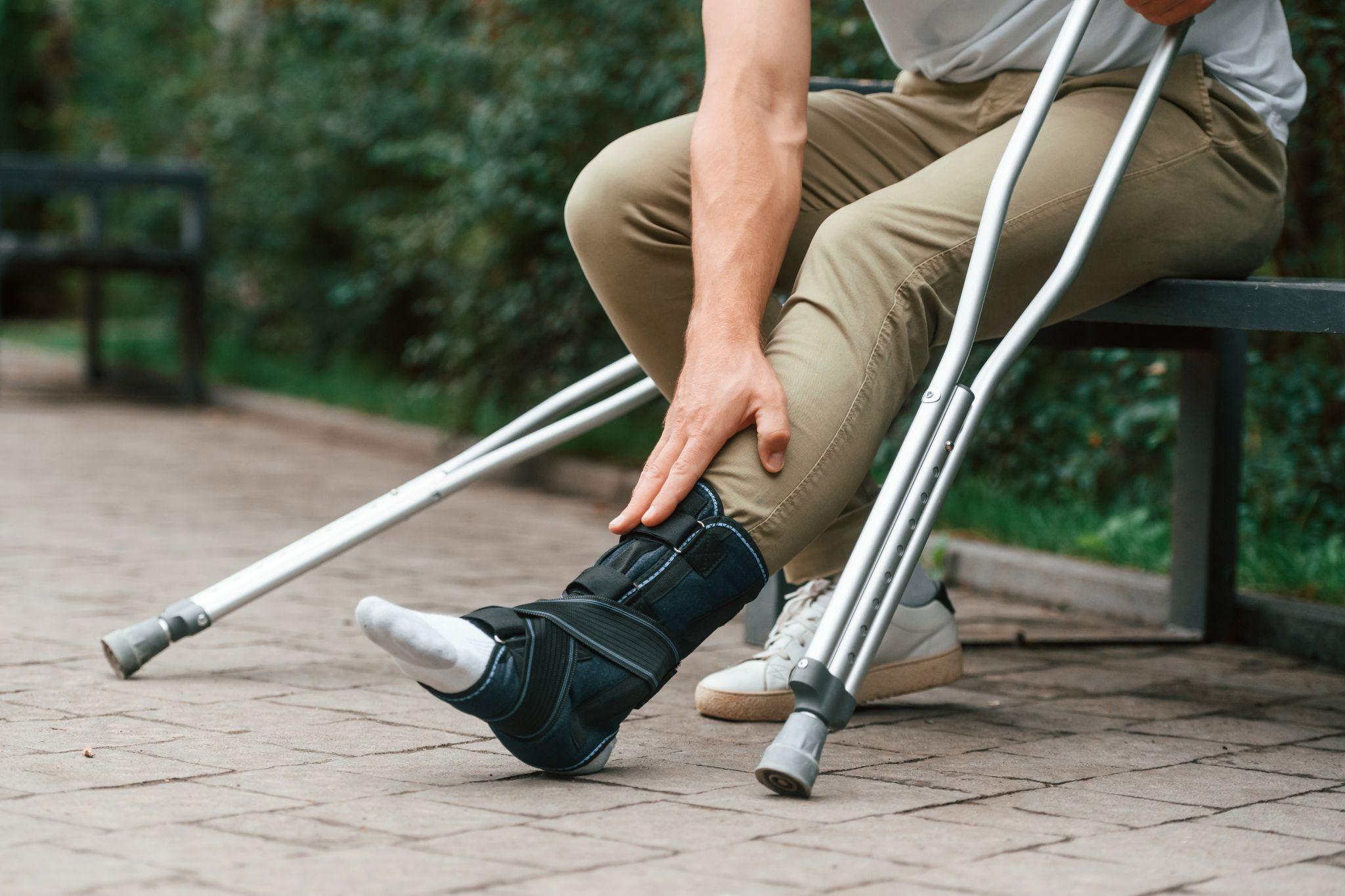 A man holding his leg with crutches.
