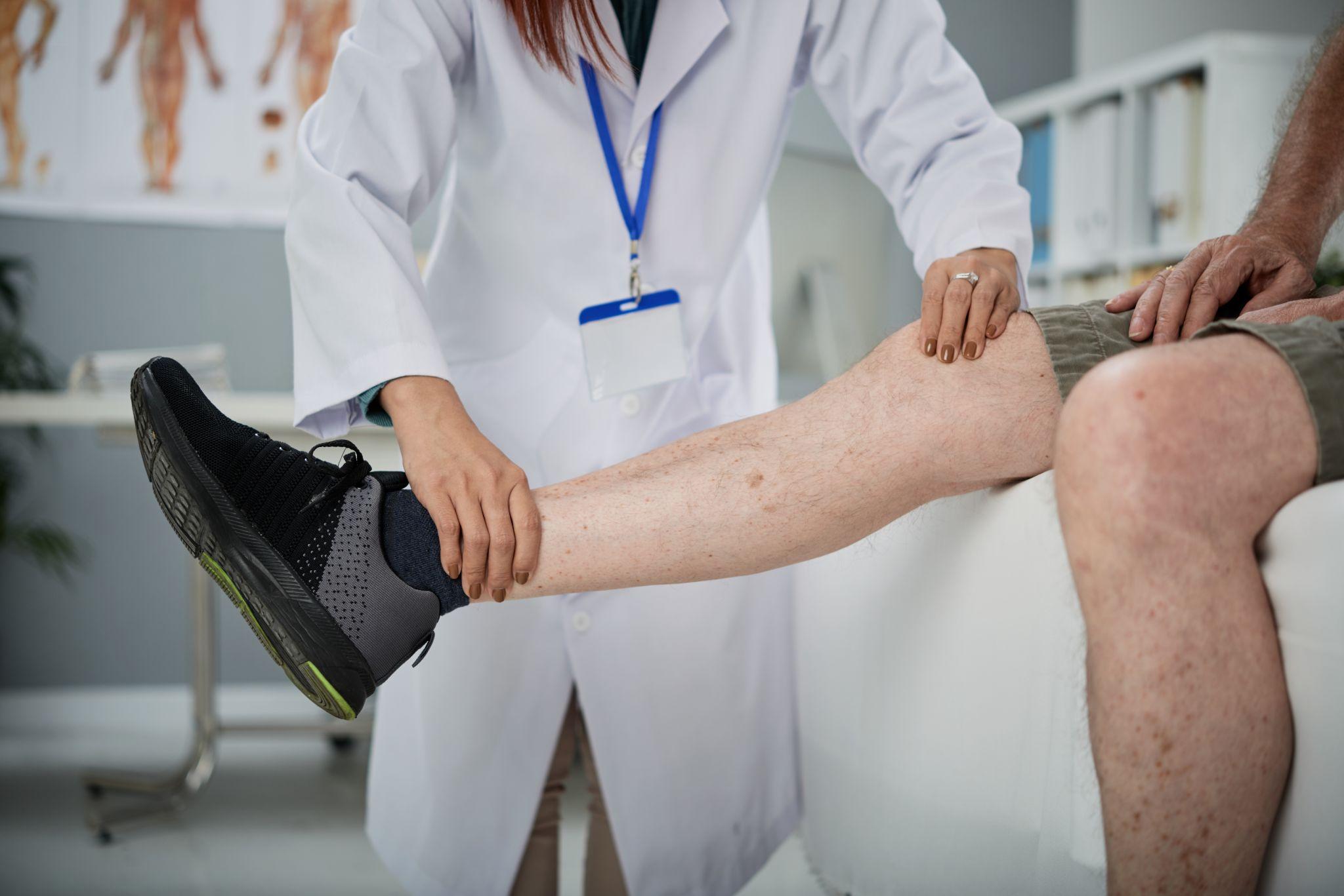 An orthopedic knee doctor guiding a man with stretches