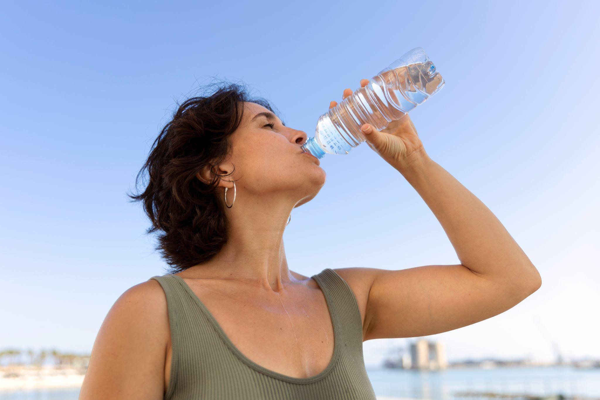 A woman drinking water from a water bottle.
