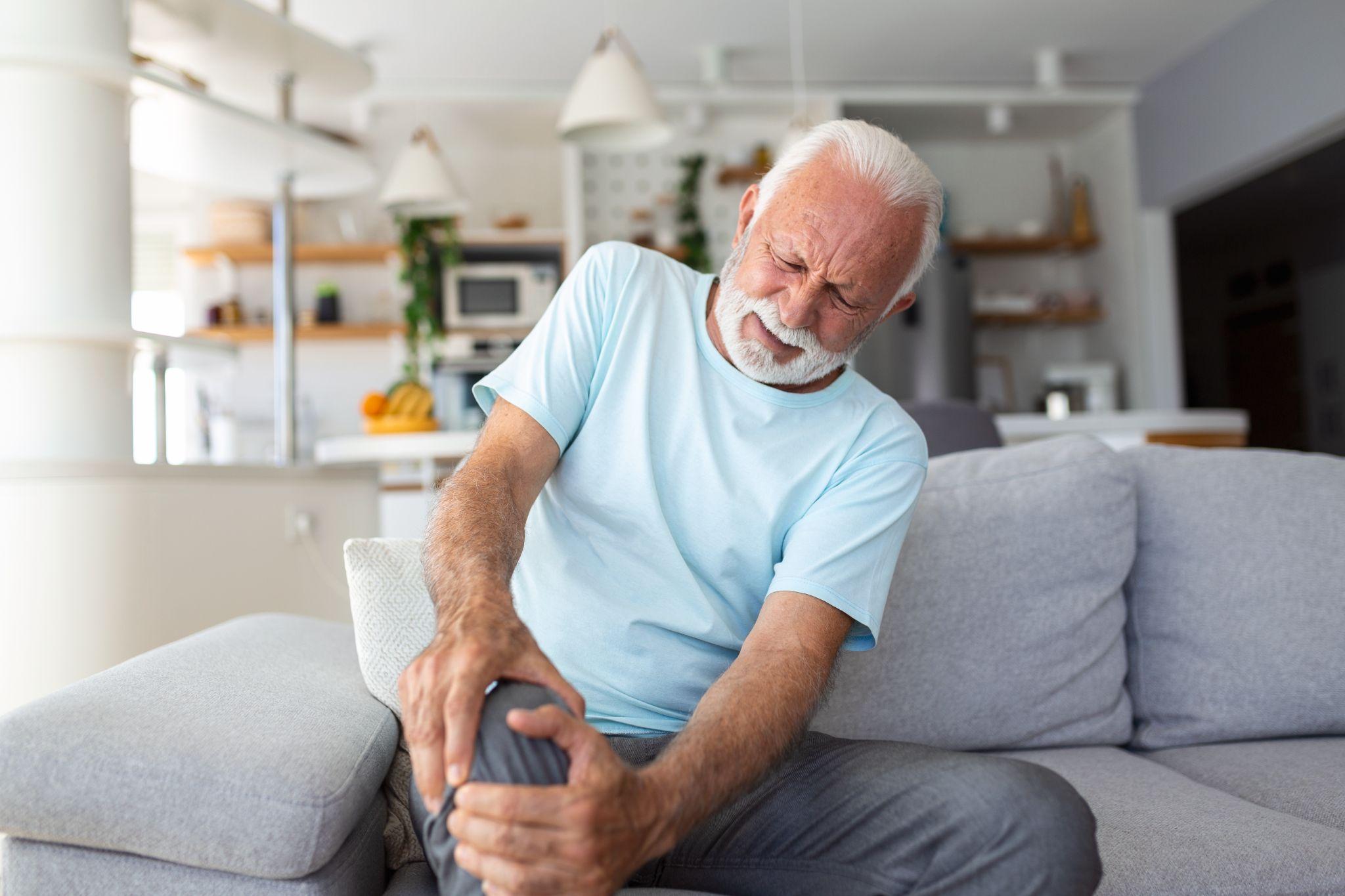 A man sitting on a sofa with knee pain.