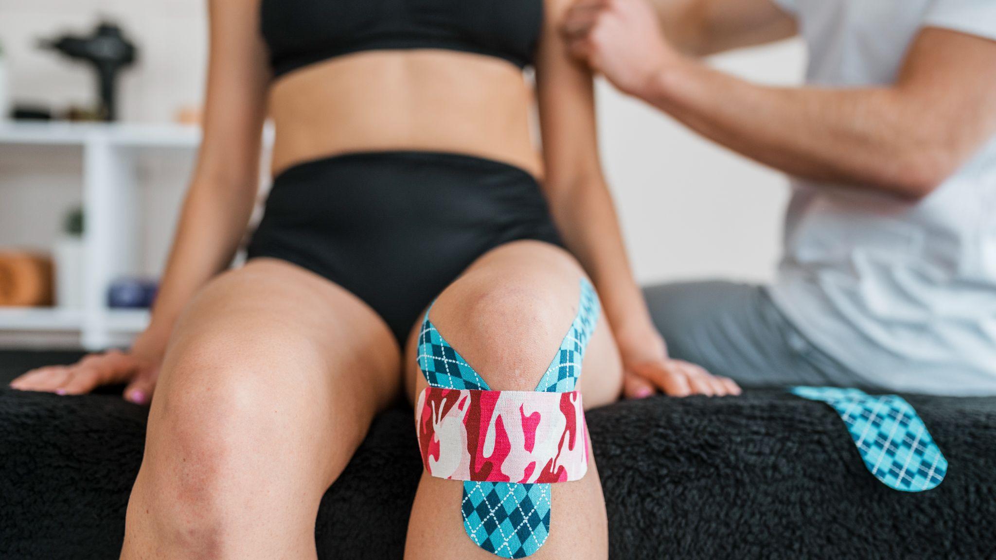 A woman with kinesiology tape on her knee.