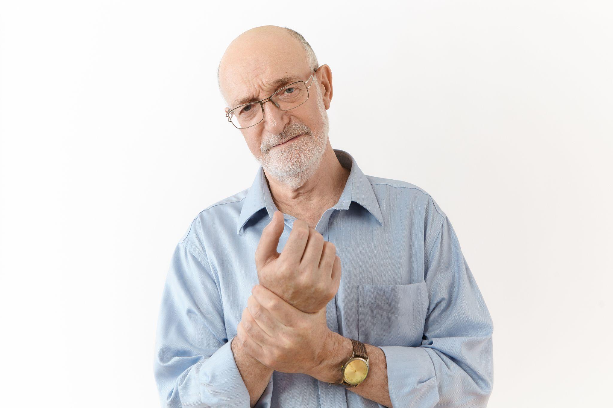 An older adult holding his own hand.