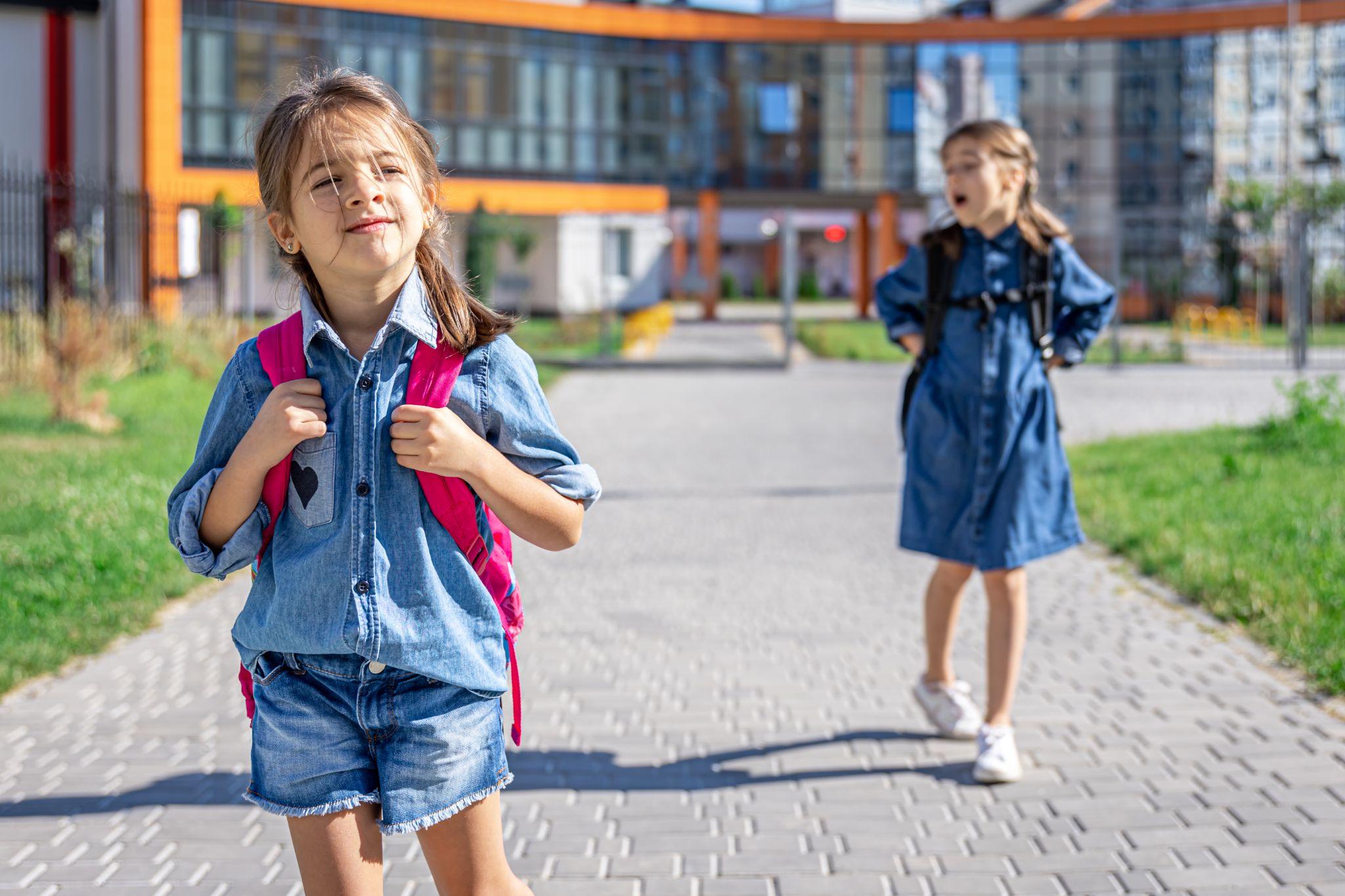 Children carrying backpacks to school.