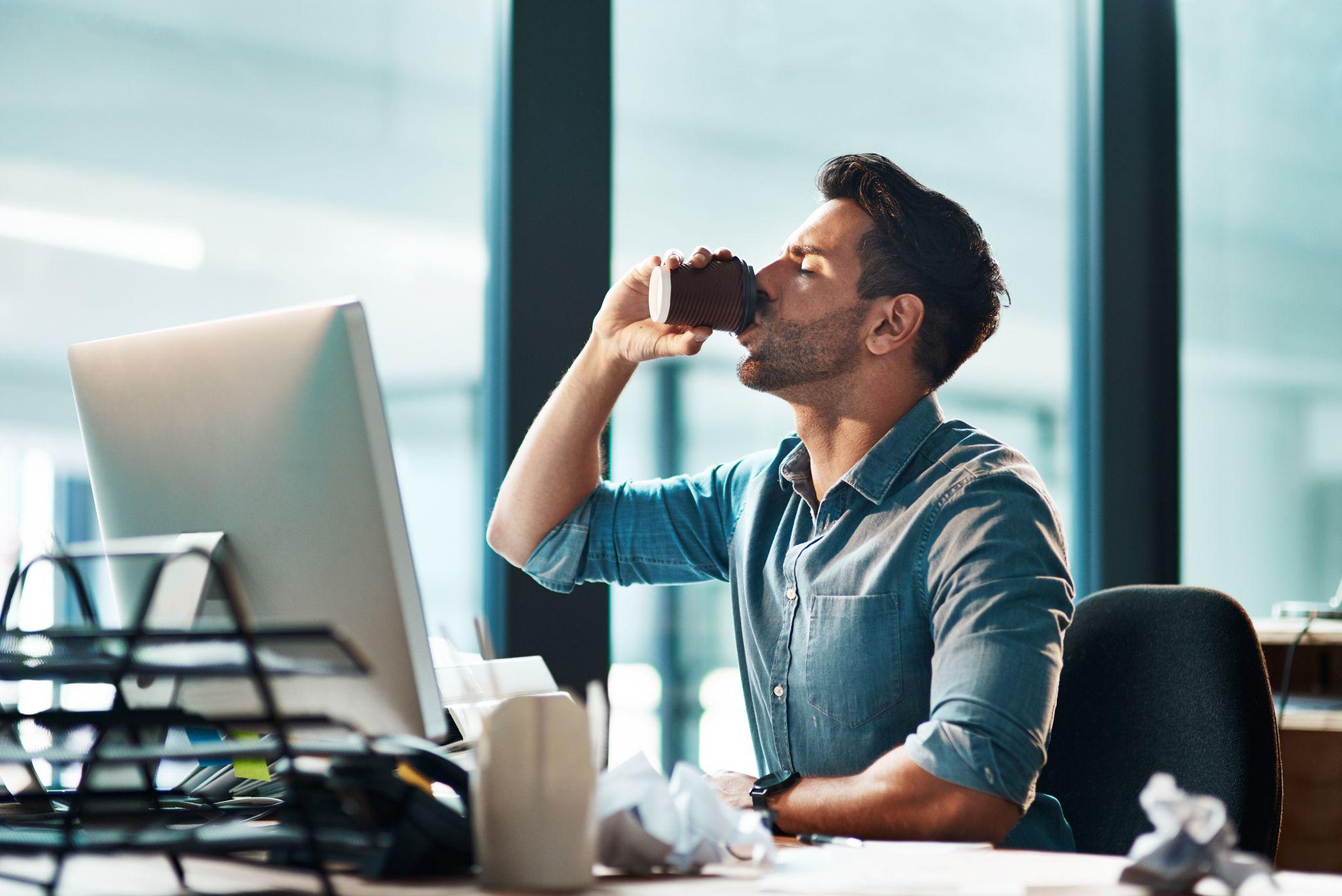 A person drinking coffee while using a laptop.