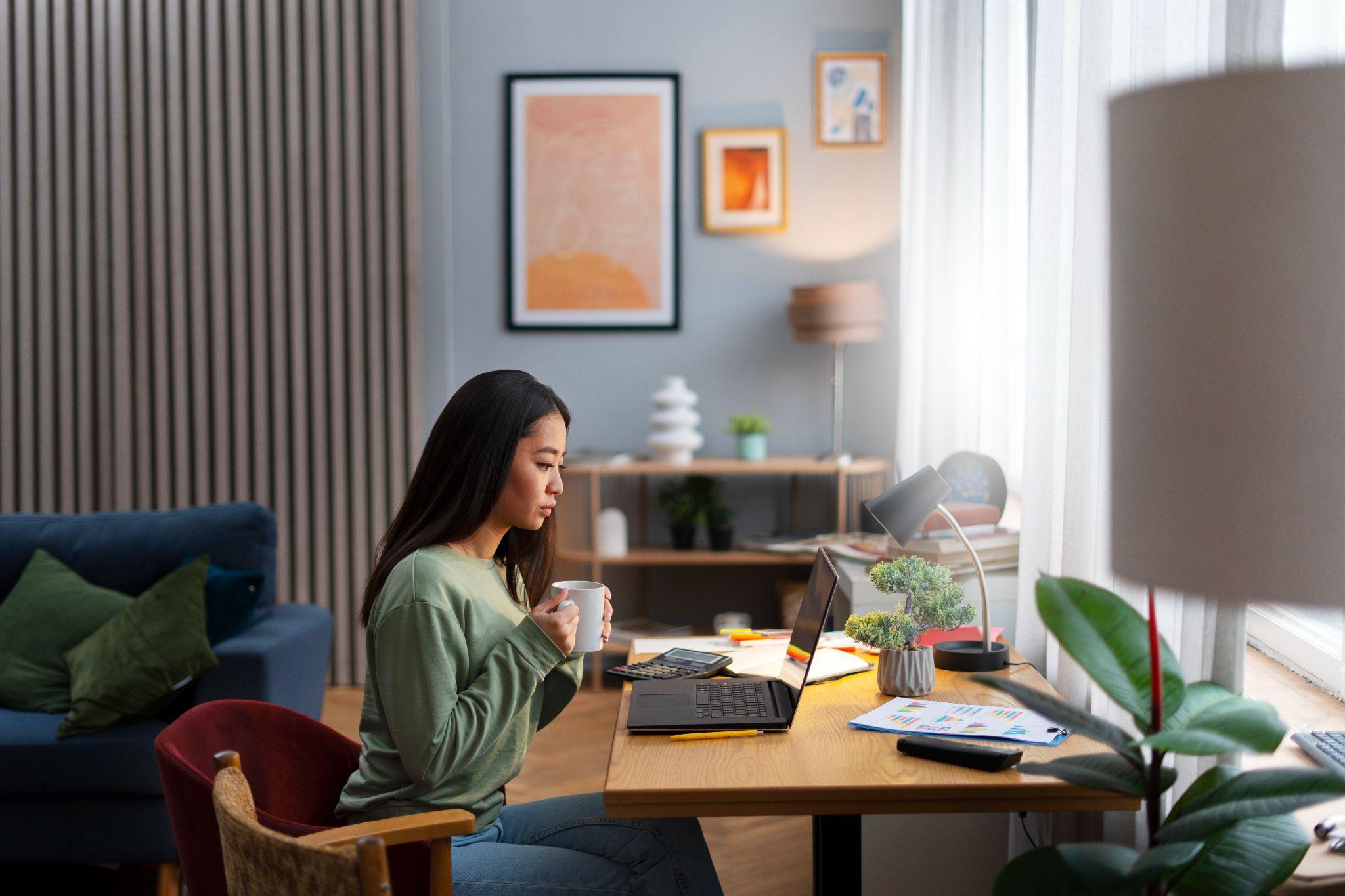 A person staring at a computer while drinking coffee.