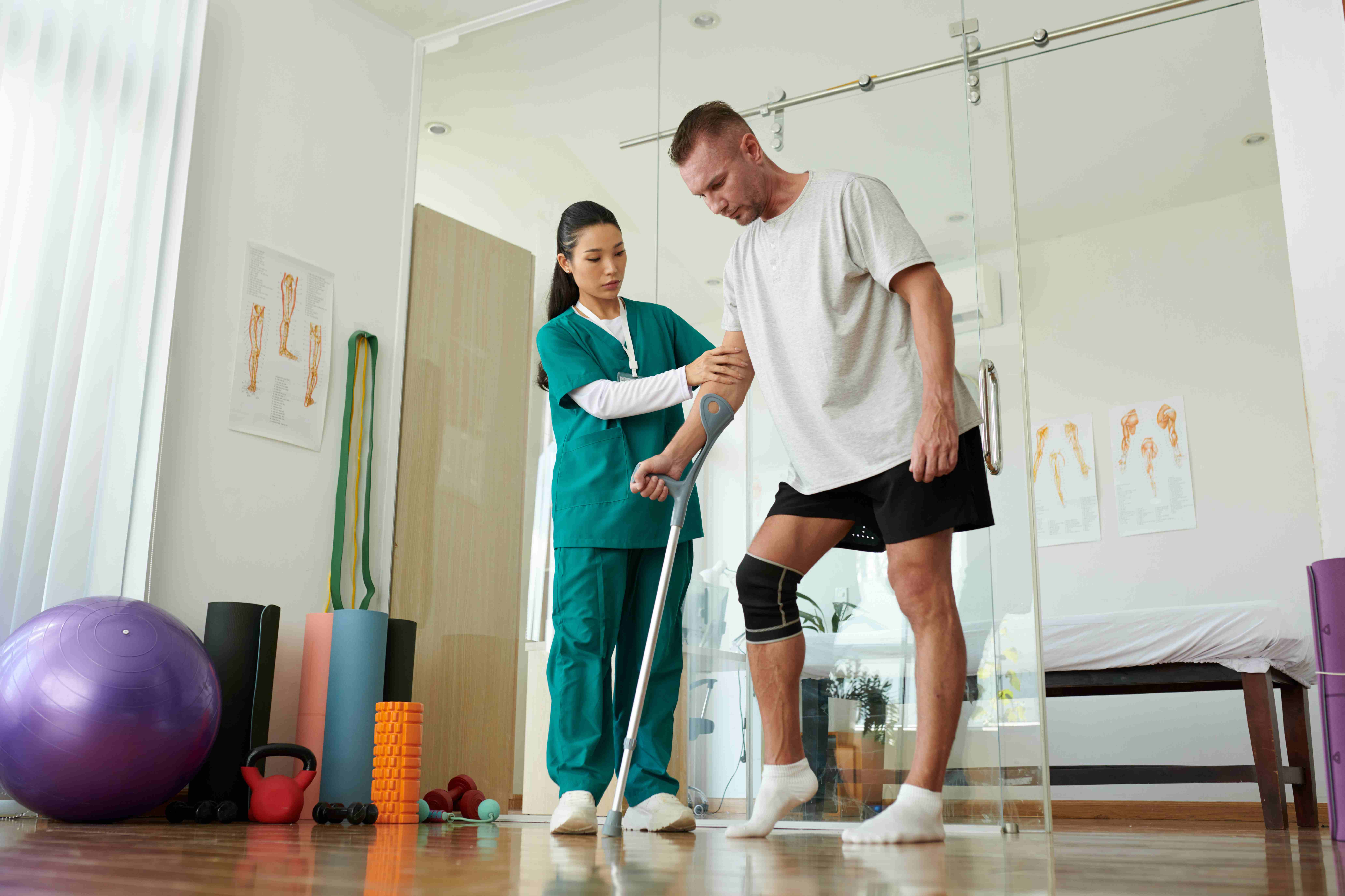  Nurse supporting a patient as they learn to walk again during knee replacement recovery.