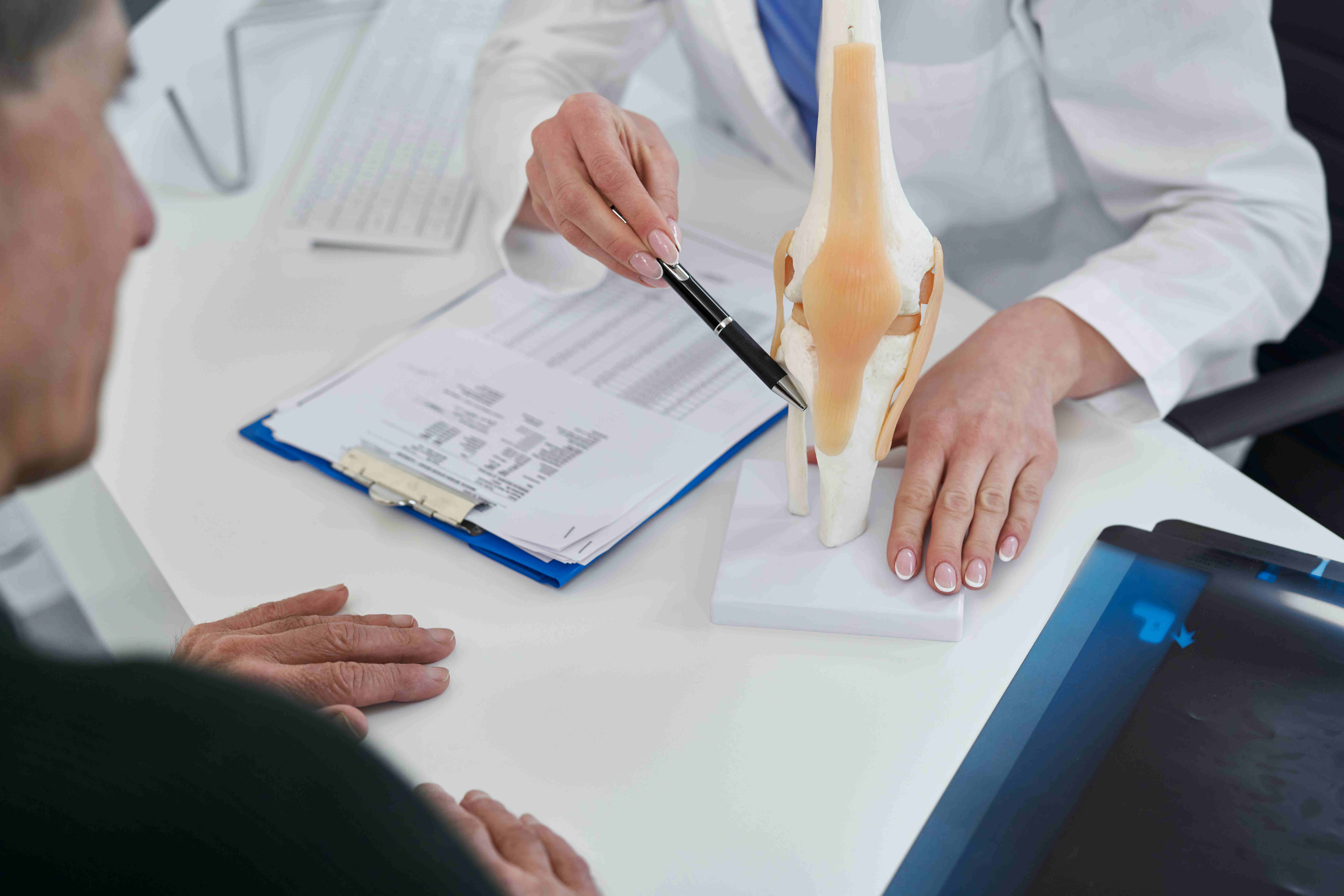  Doctor explaining bone structure to patient during a consultation about partial vs total knee replacement options