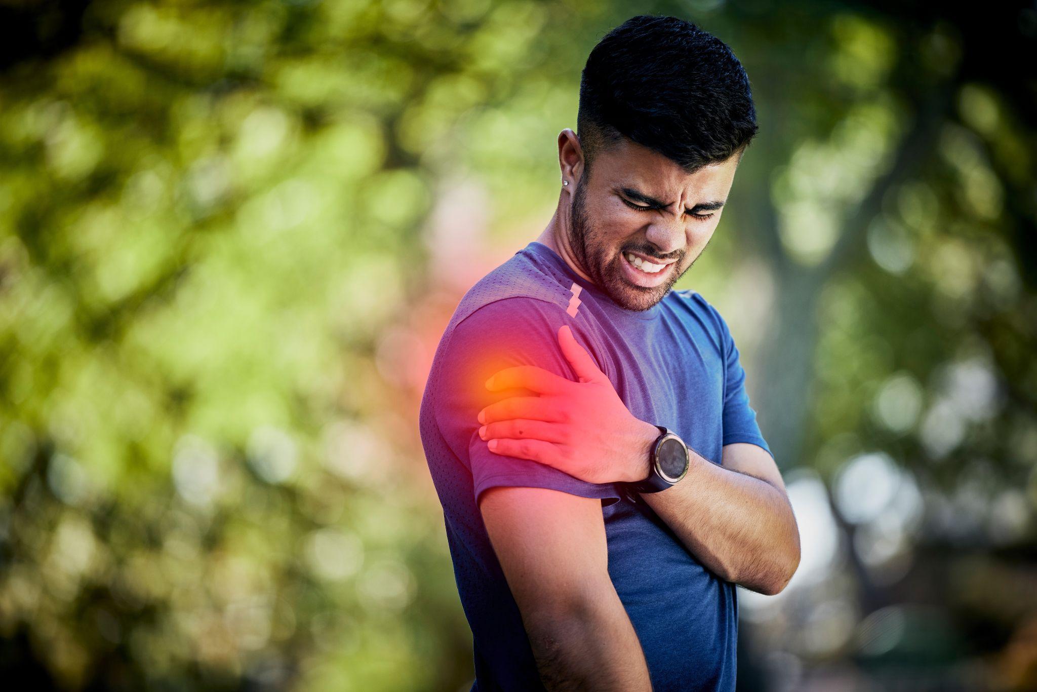 A man holding his shoulder after feeling pain during a workout session.