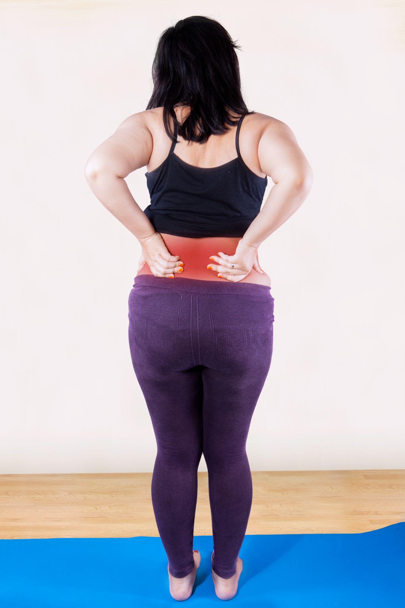 A woman experiencing lower back pain due to excess weight, highlighting the strain obesity places on the spine and joints.