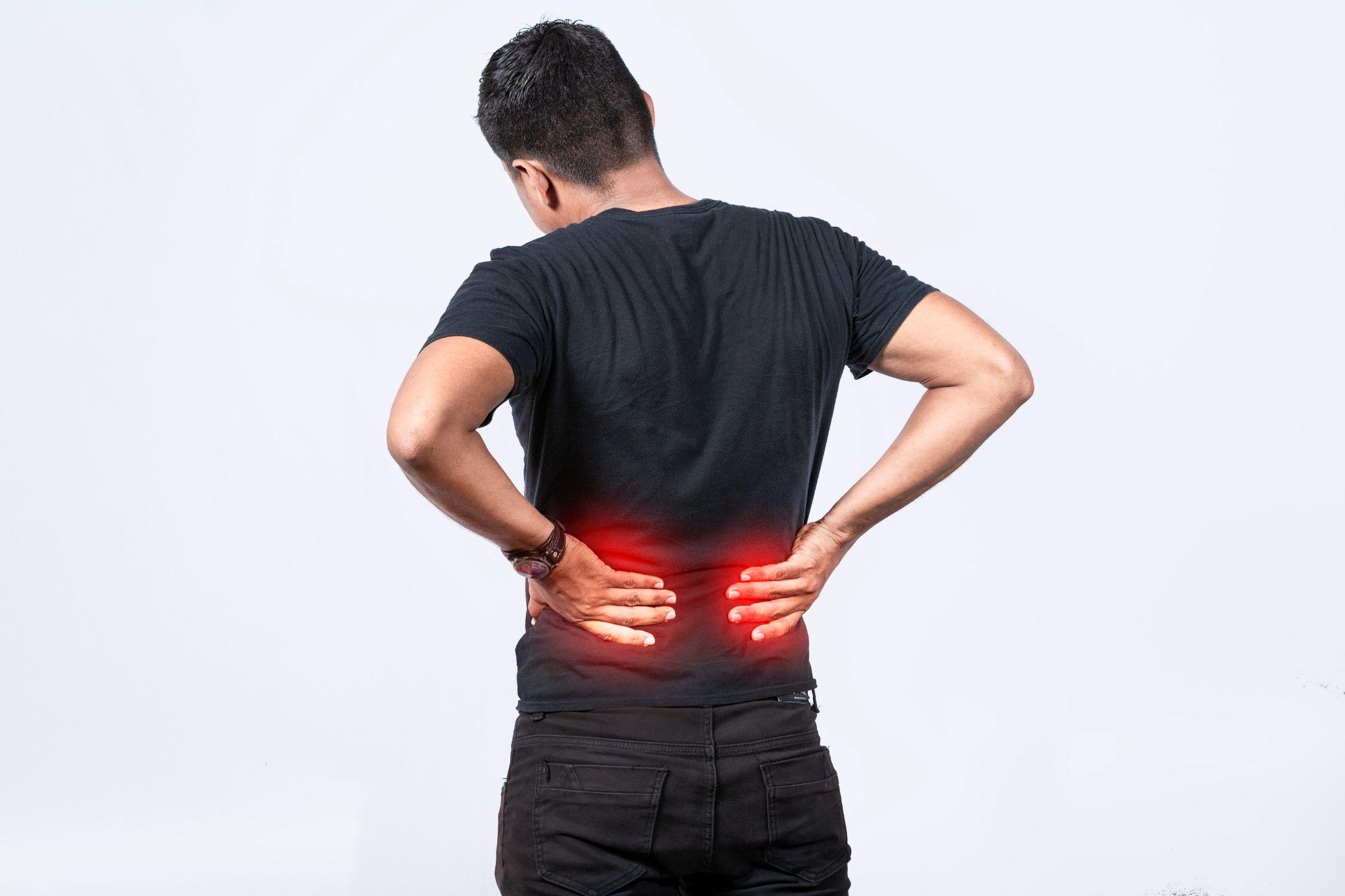 A man holding his lower back due to lumbar pain, representing spine-related problems such as muscle strain or sciatica.